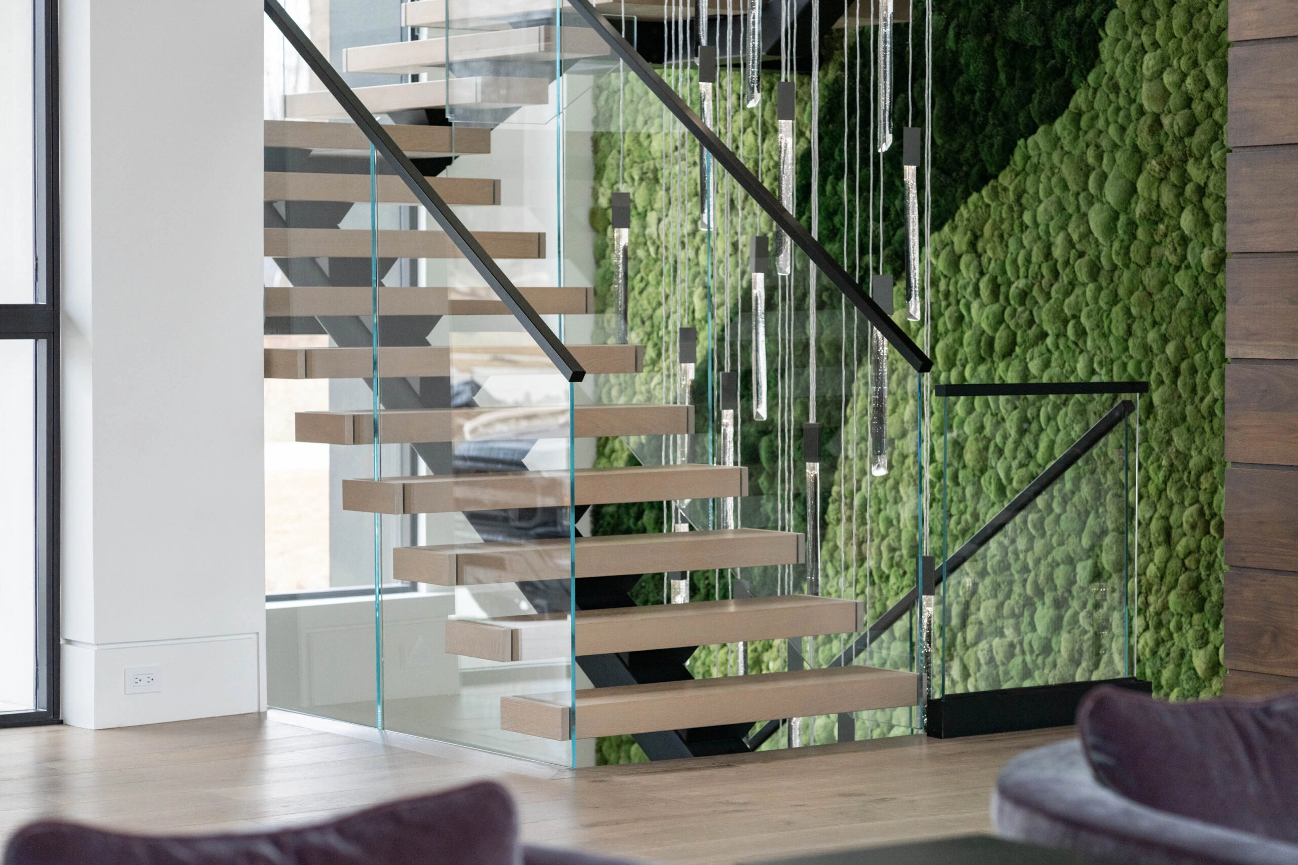 A glass railing follows a switchback stair set against a living green wall