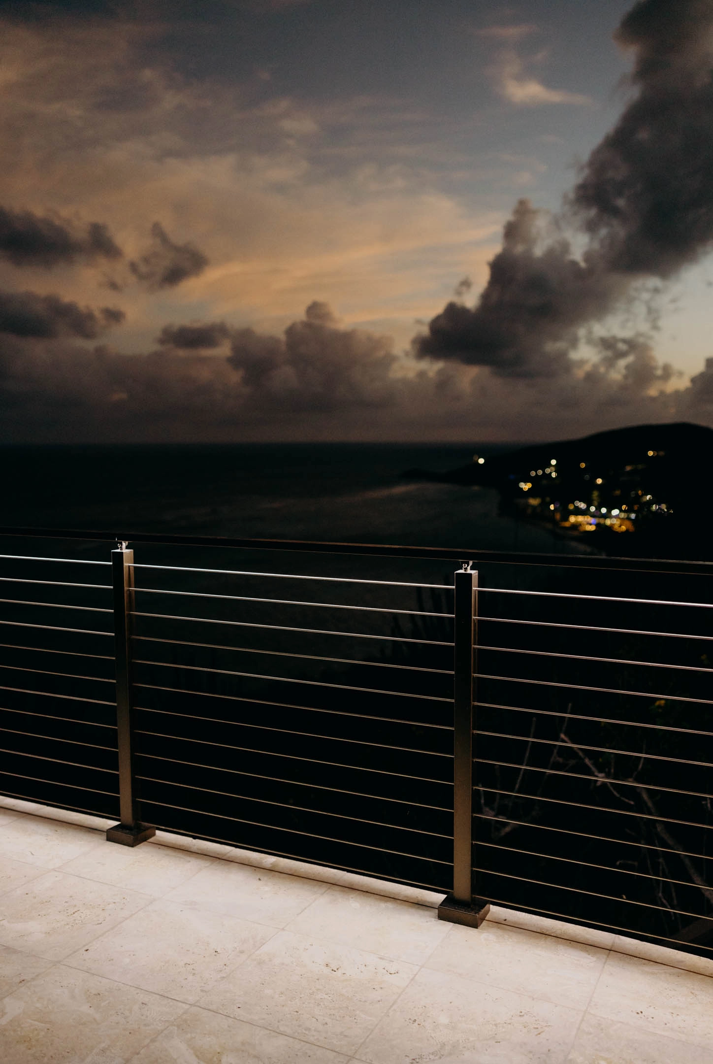 Sunset sky and distant town lights seen through slender horizontal rods