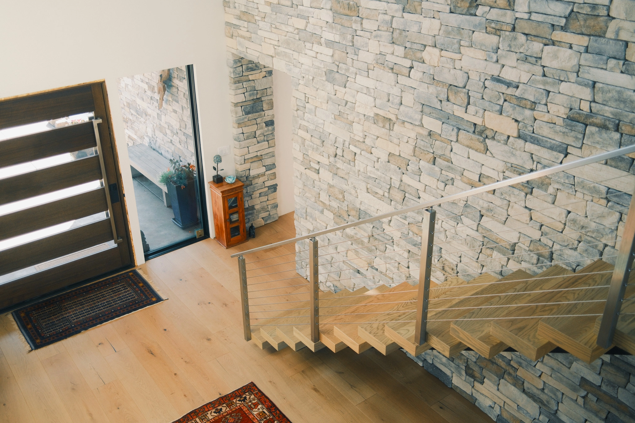 Overhead view of the entry and stair rail against a stacked stone wall
