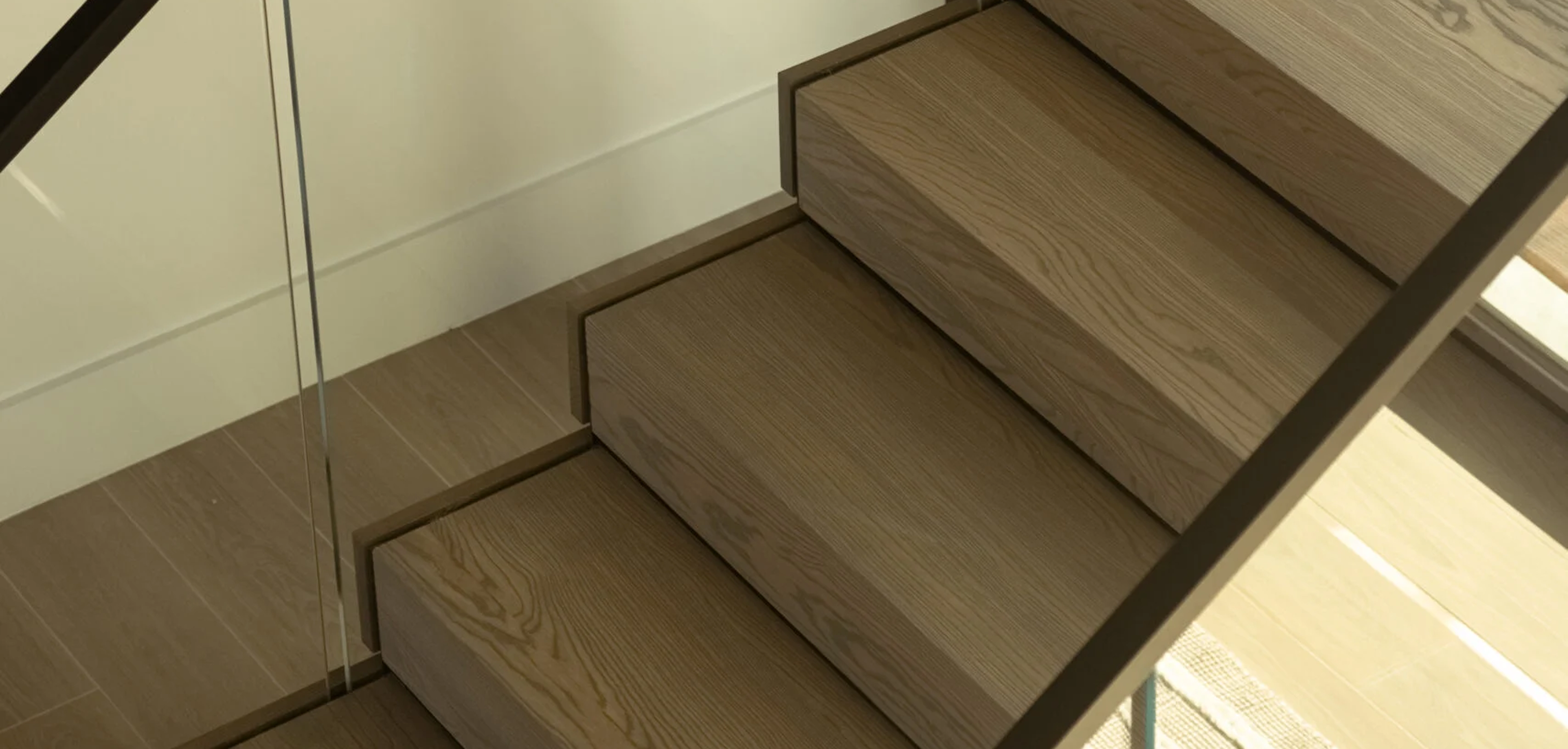 Stacked treads meet a glass panel in a tight crop of the stair edge