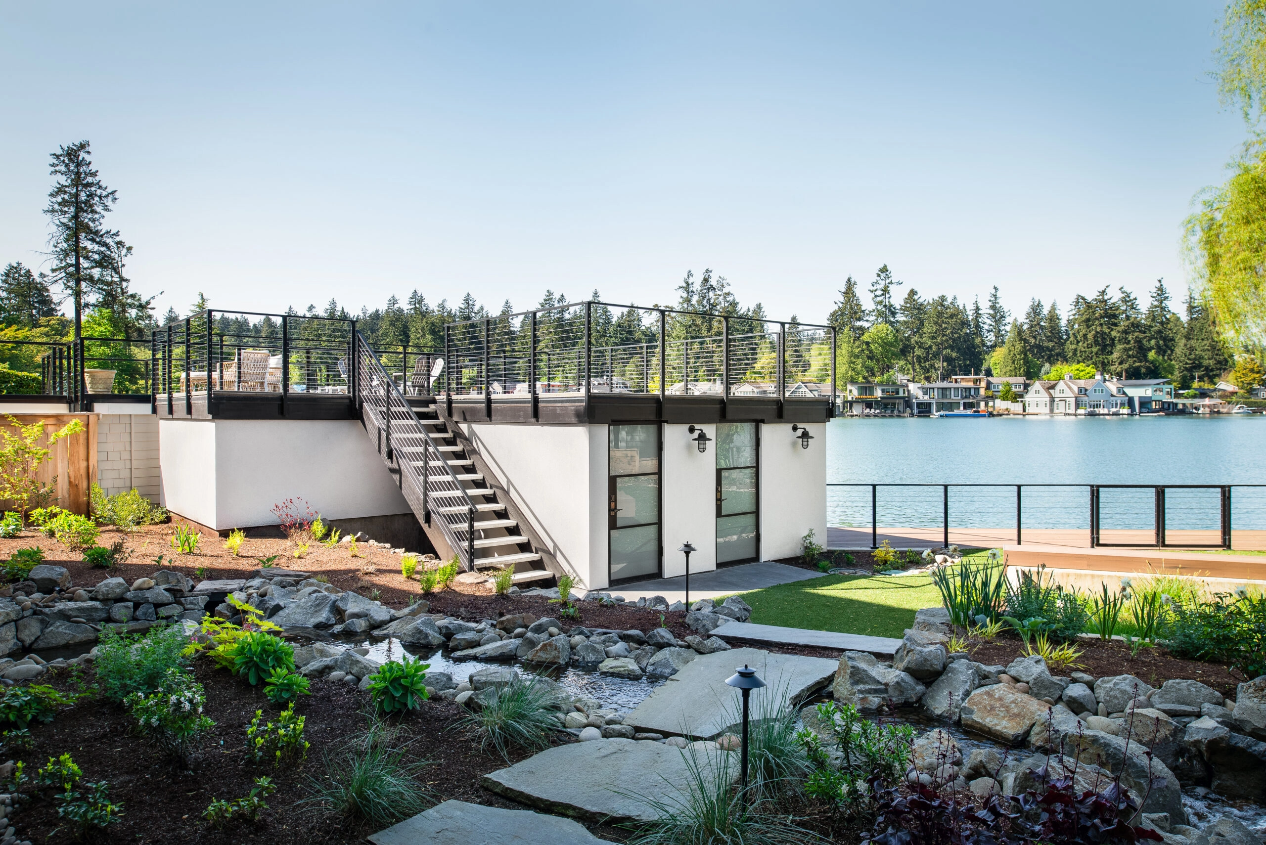 Cable railing follows steps down to a lakefront lawn and dock