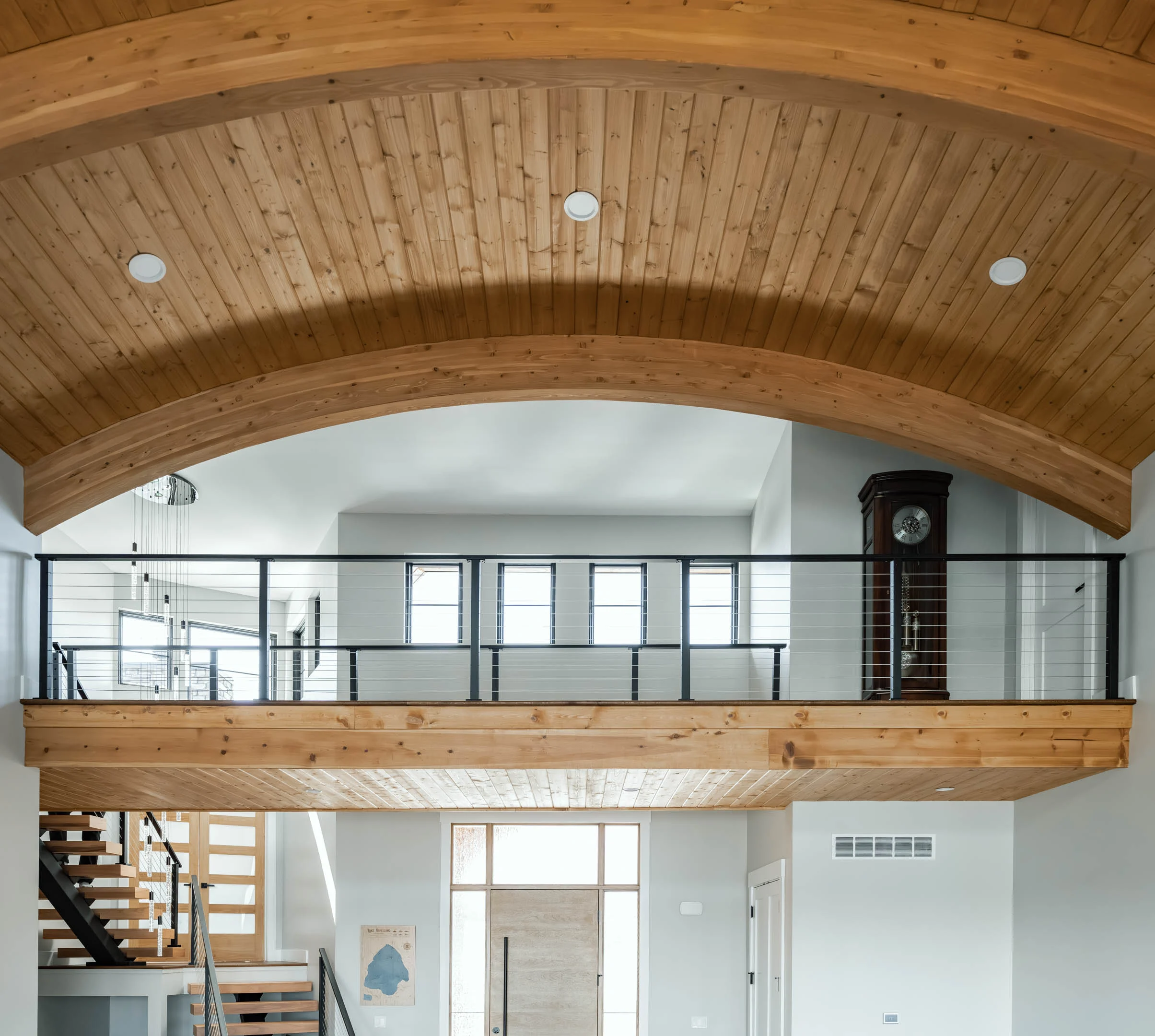 Cable railing edges a loft beneath a barrel-vaulted wood ceiling