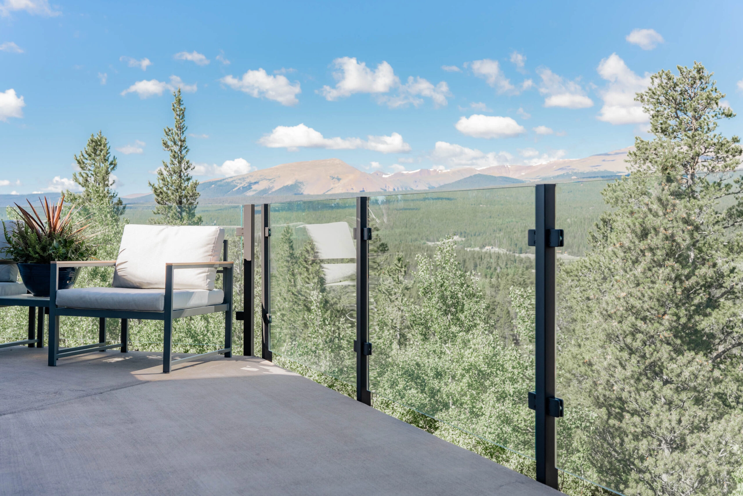 Glass panels in black posts open a deck to a wide mountain horizon