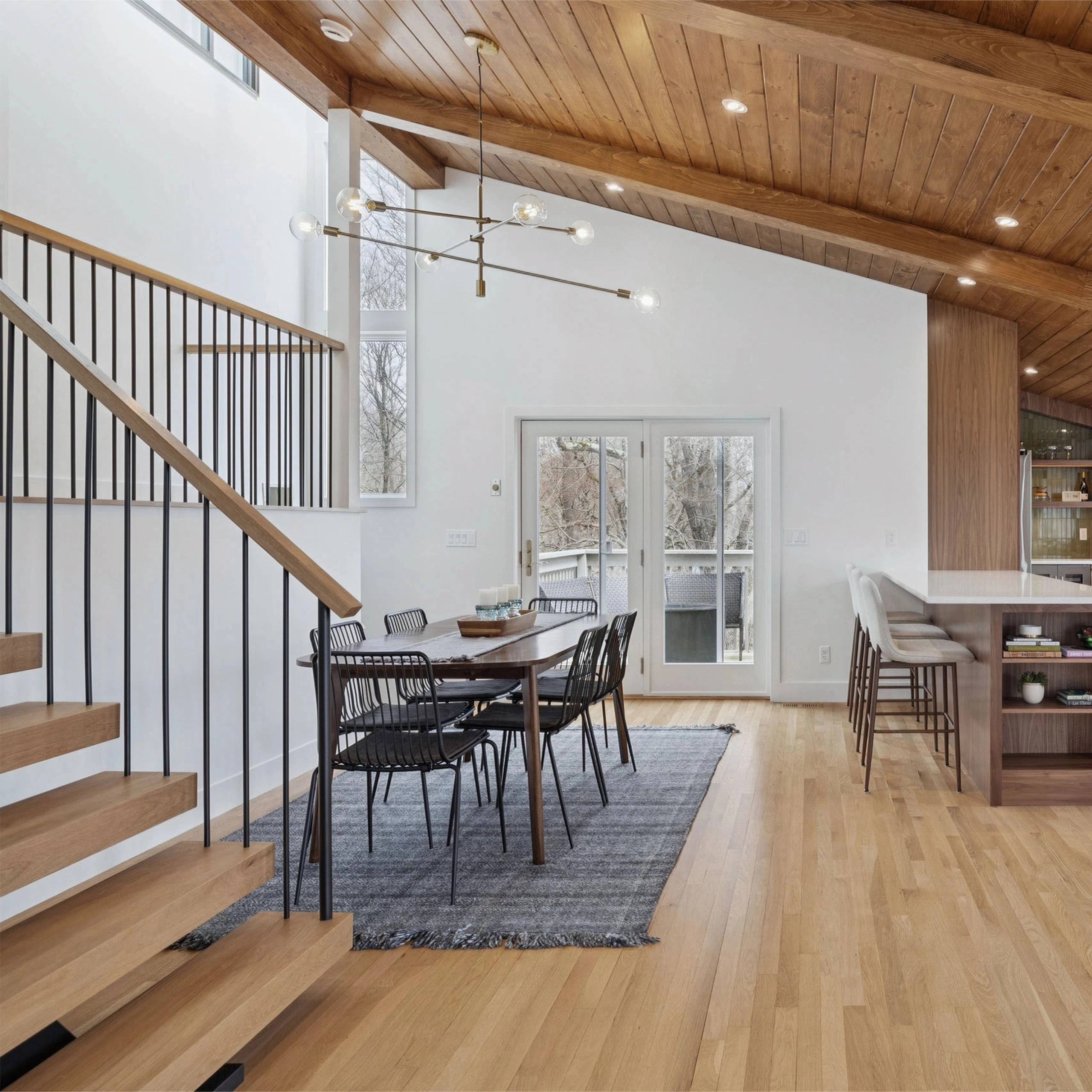 After: a floating stair with slim balusters opens onto a vaulted dining room