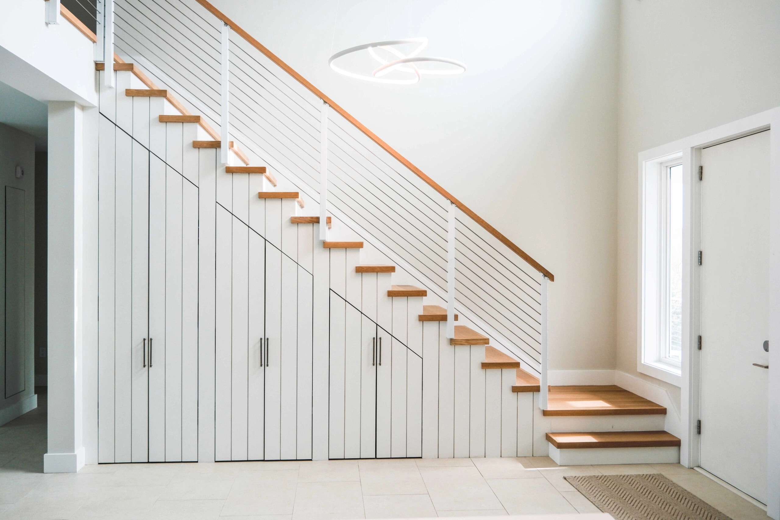 Side-mounted rod railing and a wood cap run above built-in entry cabinets