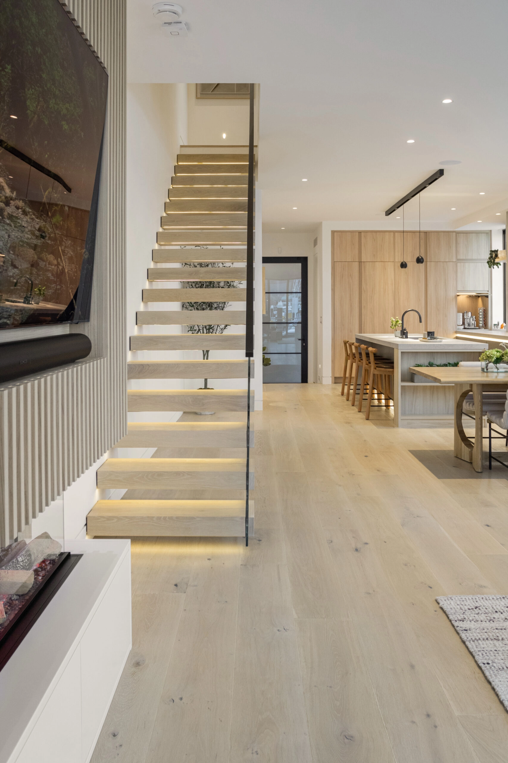 Cantilevered treads and a glass panel line a hallway leading to the kitchen