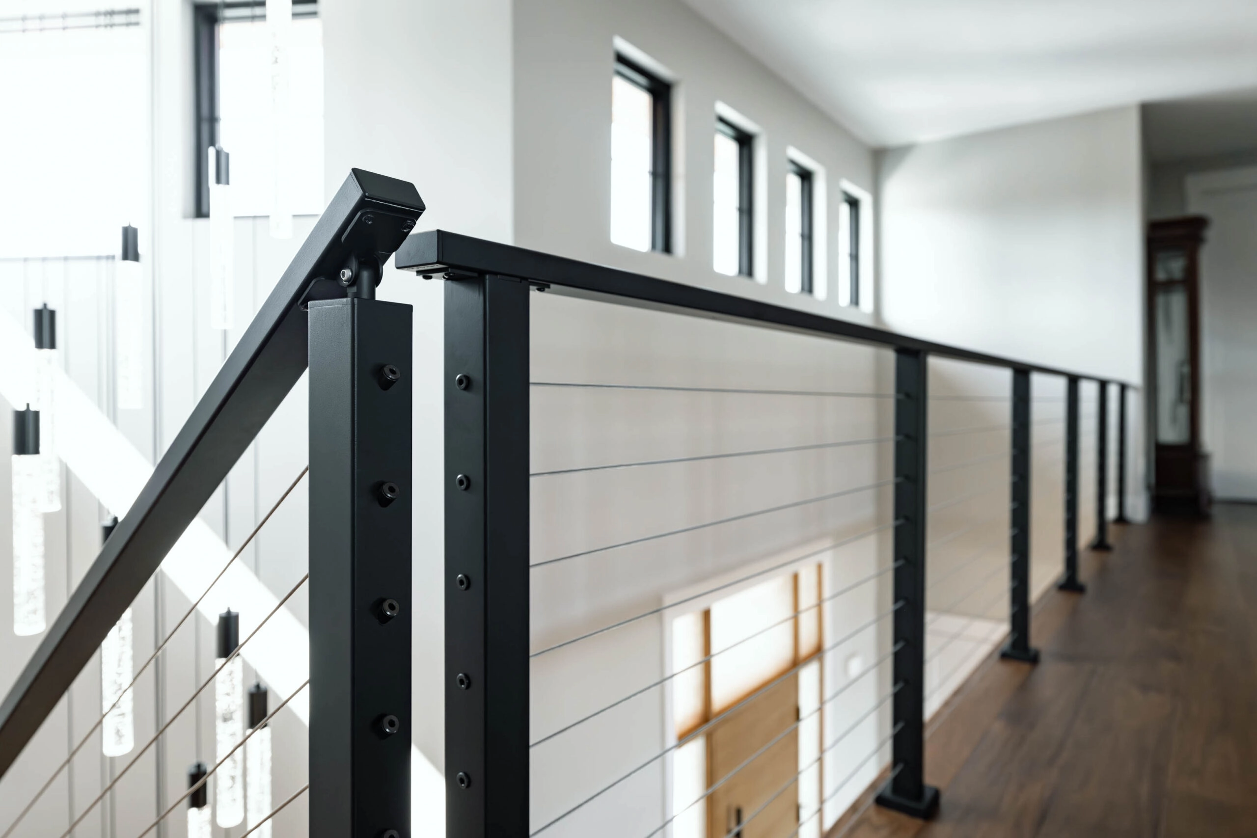 Black posts and cable infill guard an interior catwalk above a plank wall