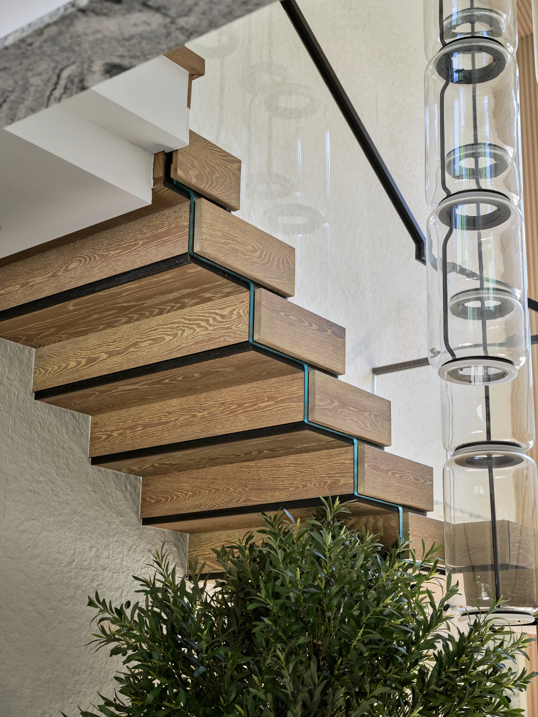 Seen from below, glass sits flush between treads beside a string of pendants