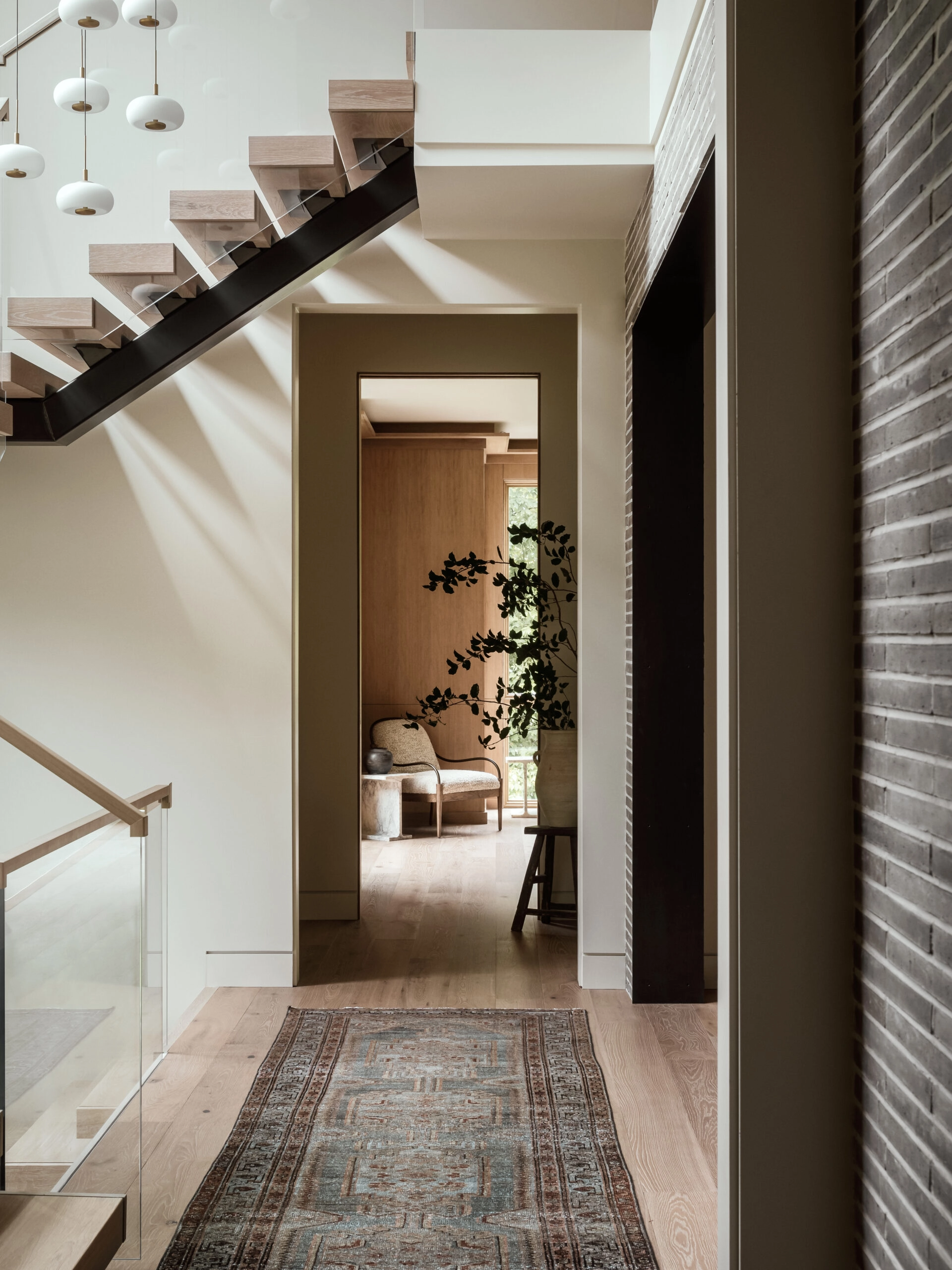 A floating stair crosses above a hallway hung with clustered pendants