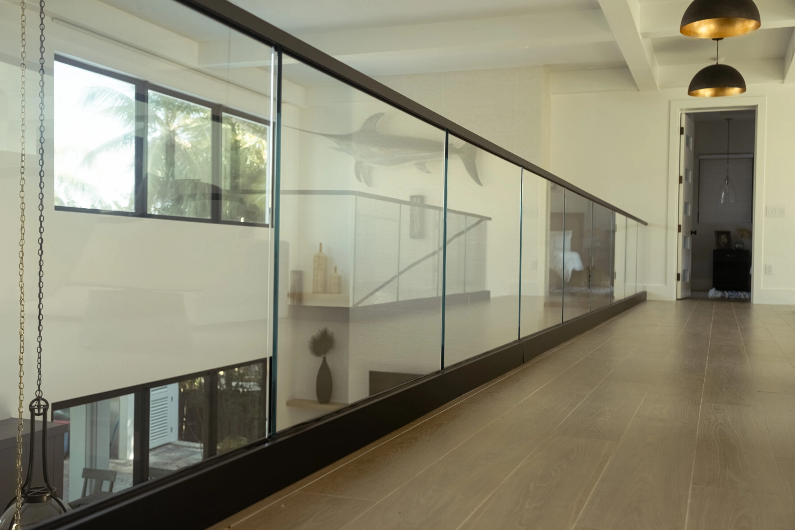 Glass panels in a black base rail run the length of an upper hallway