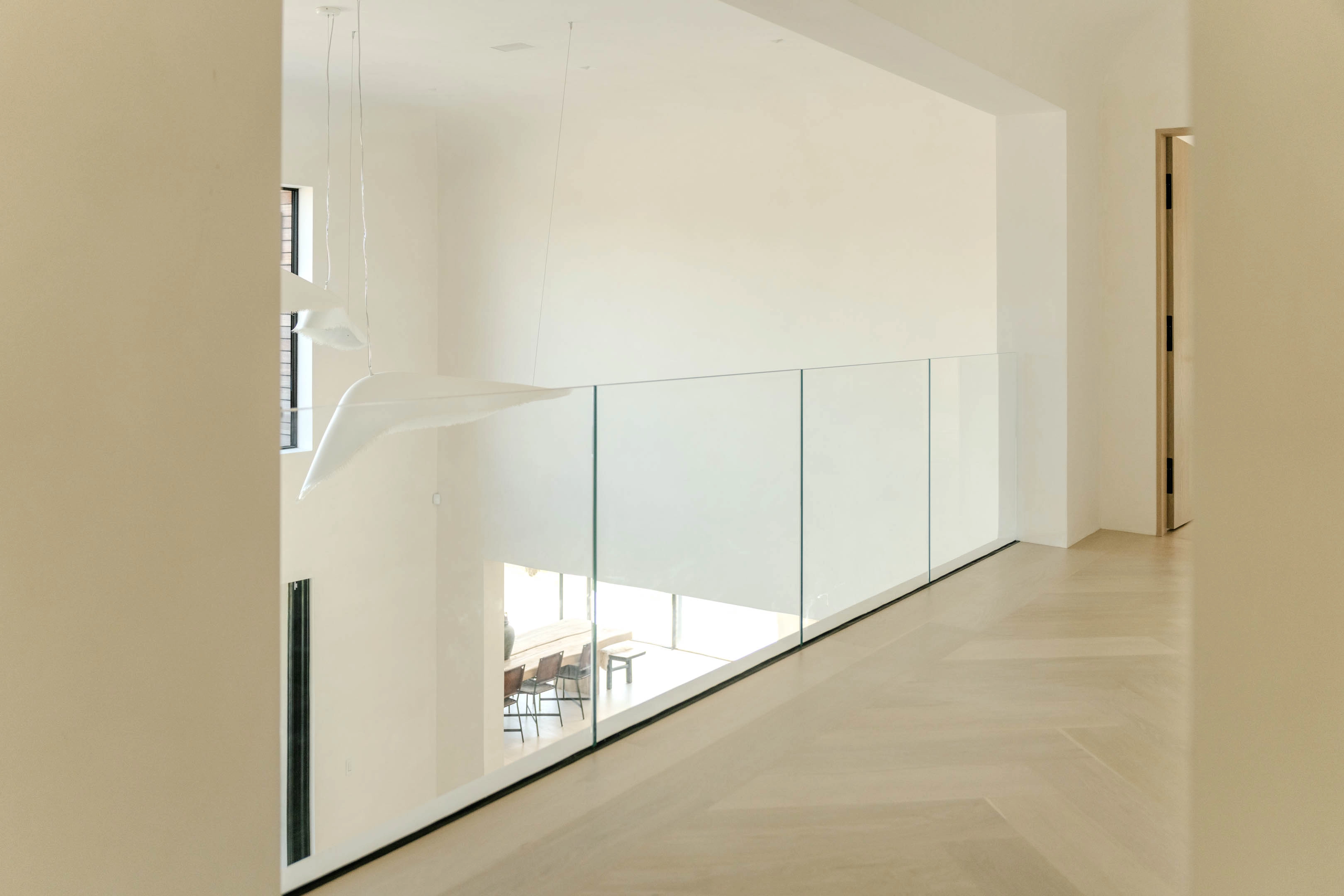 A glass railing follows an upper hallway with brackets kept out of sight