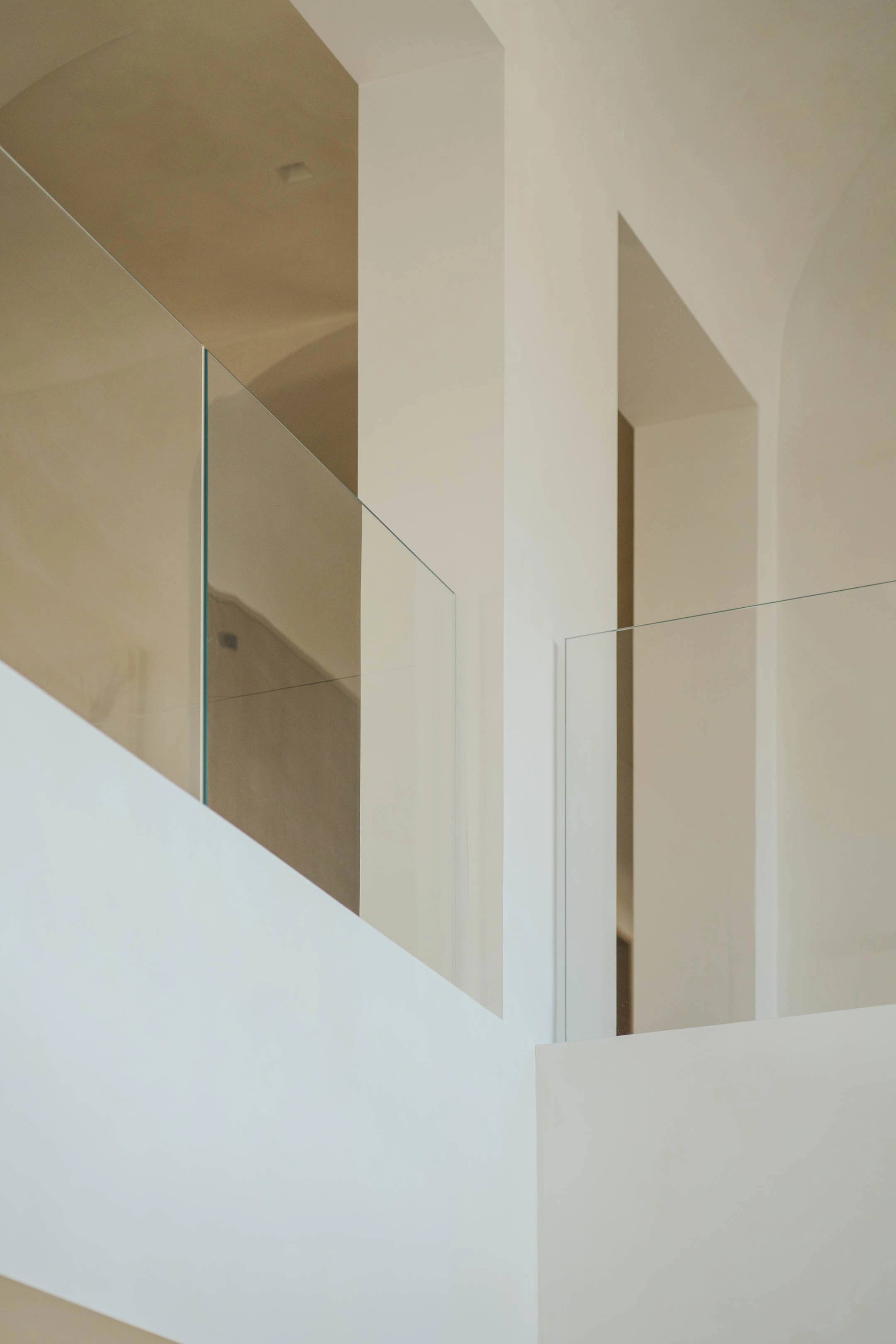 Glass panels meet plaster walls at a stair opening with no visible hardware