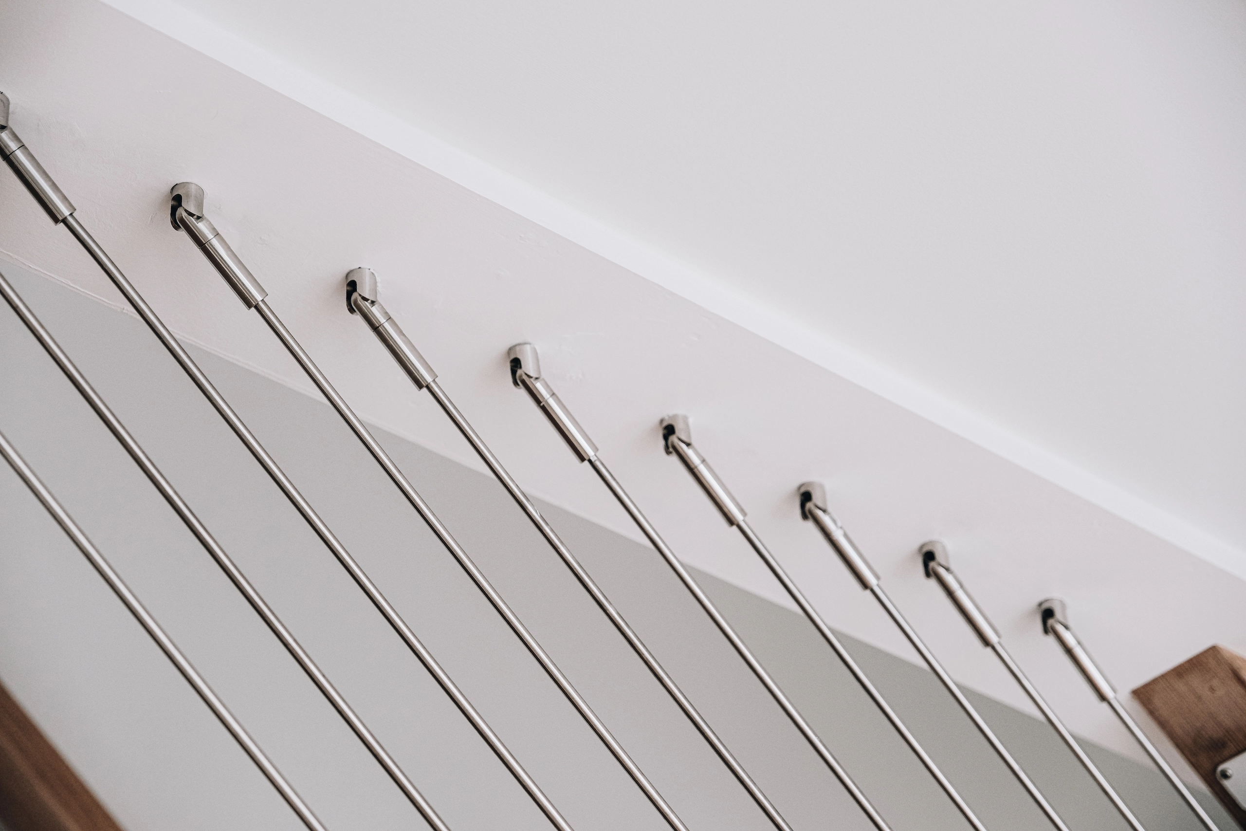 Angled rods land in a white wall along a stair in polished terminals