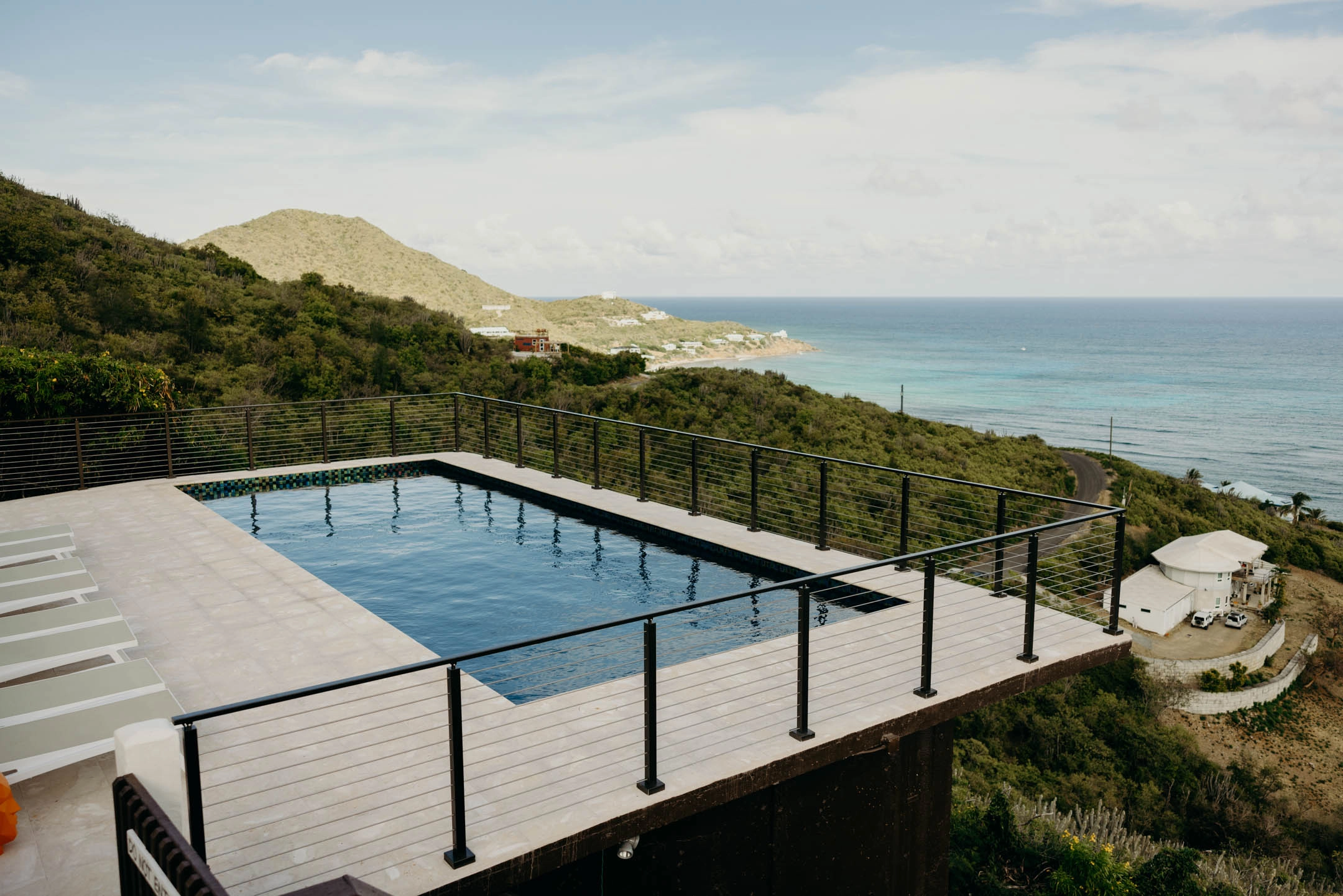 Elevated view of a pool deck ringed by rod railing above a bay