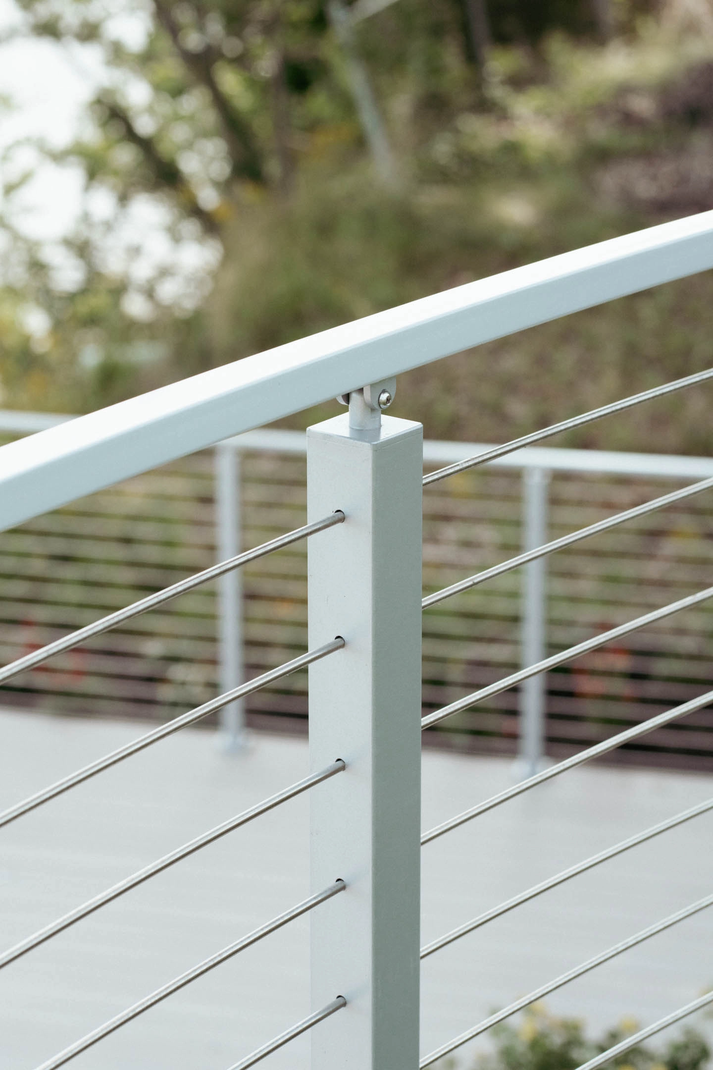 White posts carry rod infill beneath a gently curved top rail outdoors