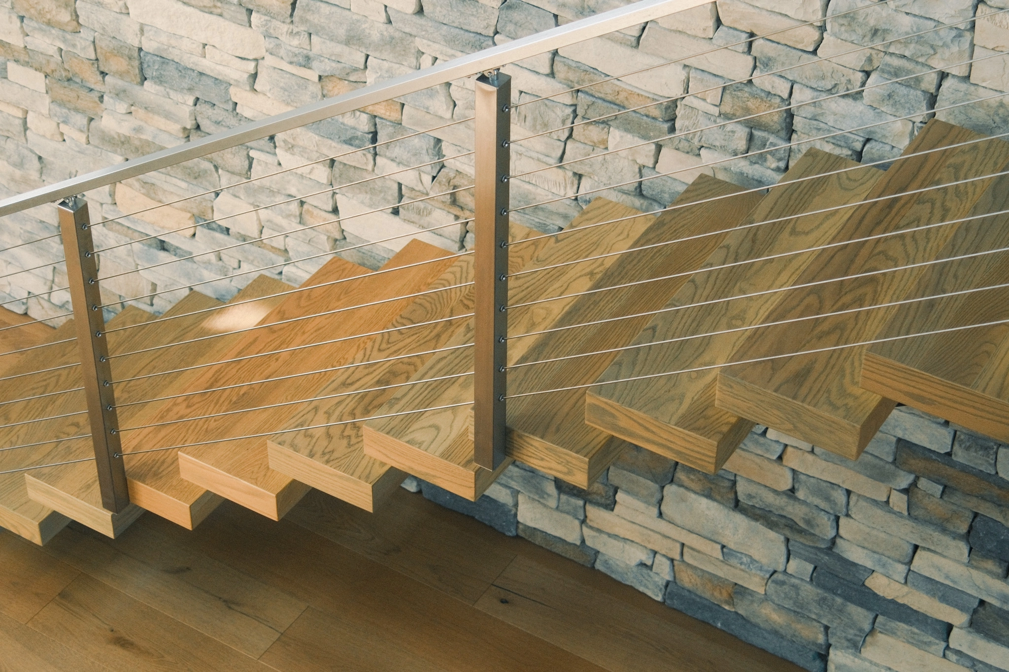 Treads and taut cables seen from above against the pale stone wall