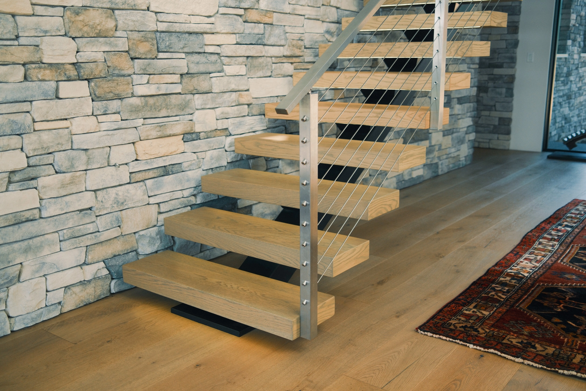 Lower steps and landing of the floating stair against stacked stone