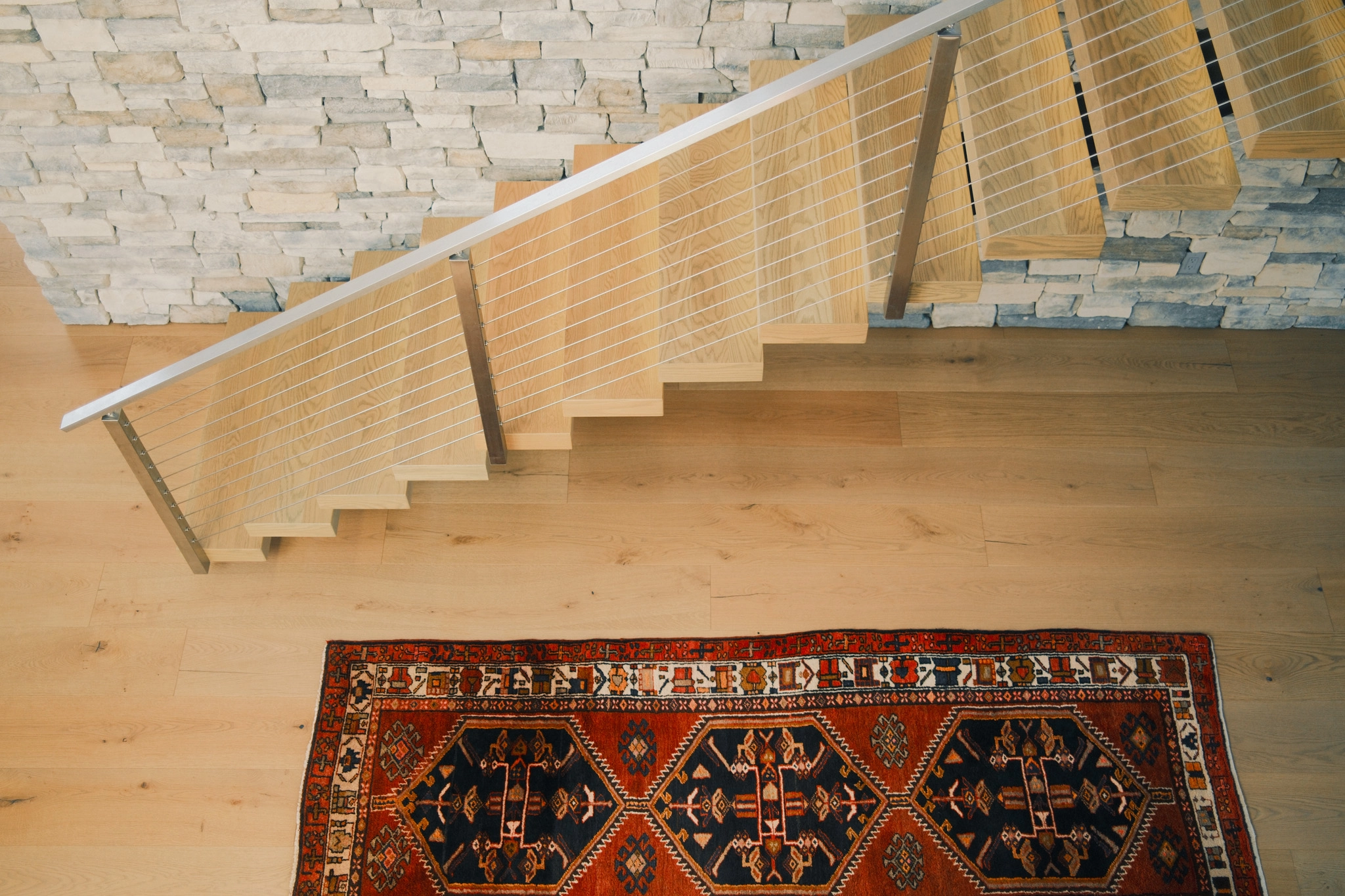 Top-down view of the flight, handrail and a patterned rug below