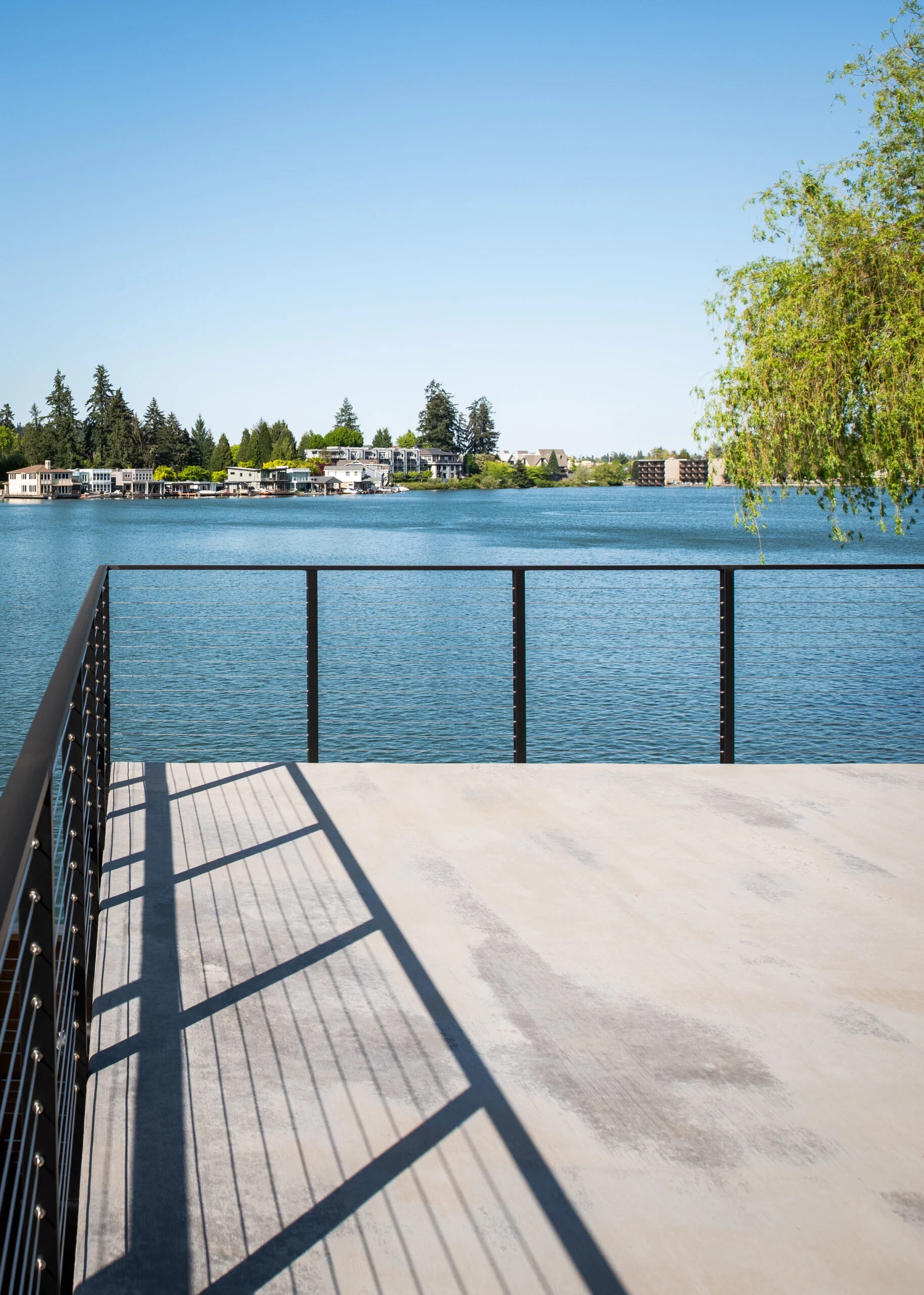 Railing casting shadows across a concrete patio at the water's edge
