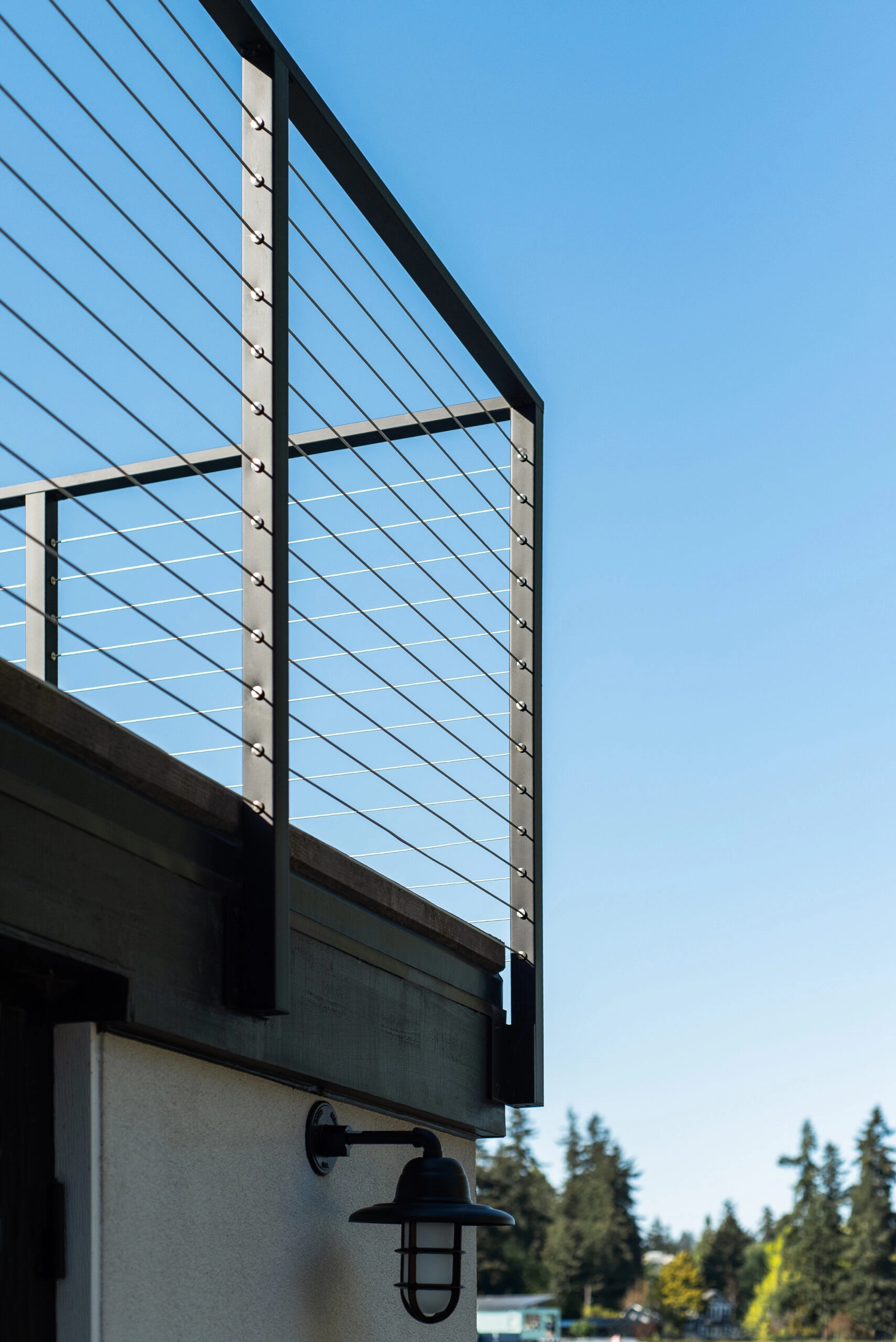 Roof deck railing against clear sky above a caged wall sconce