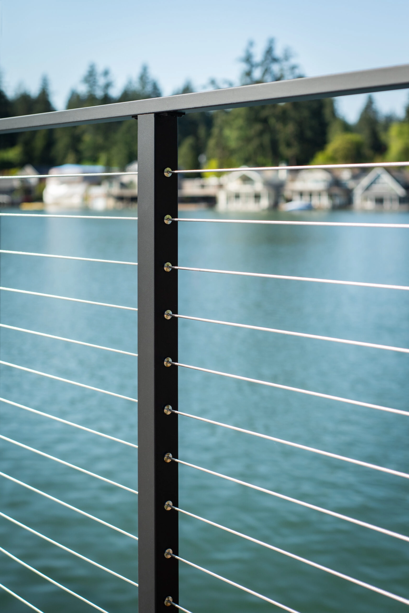 Black post detail with cables stretching toward homes across the water