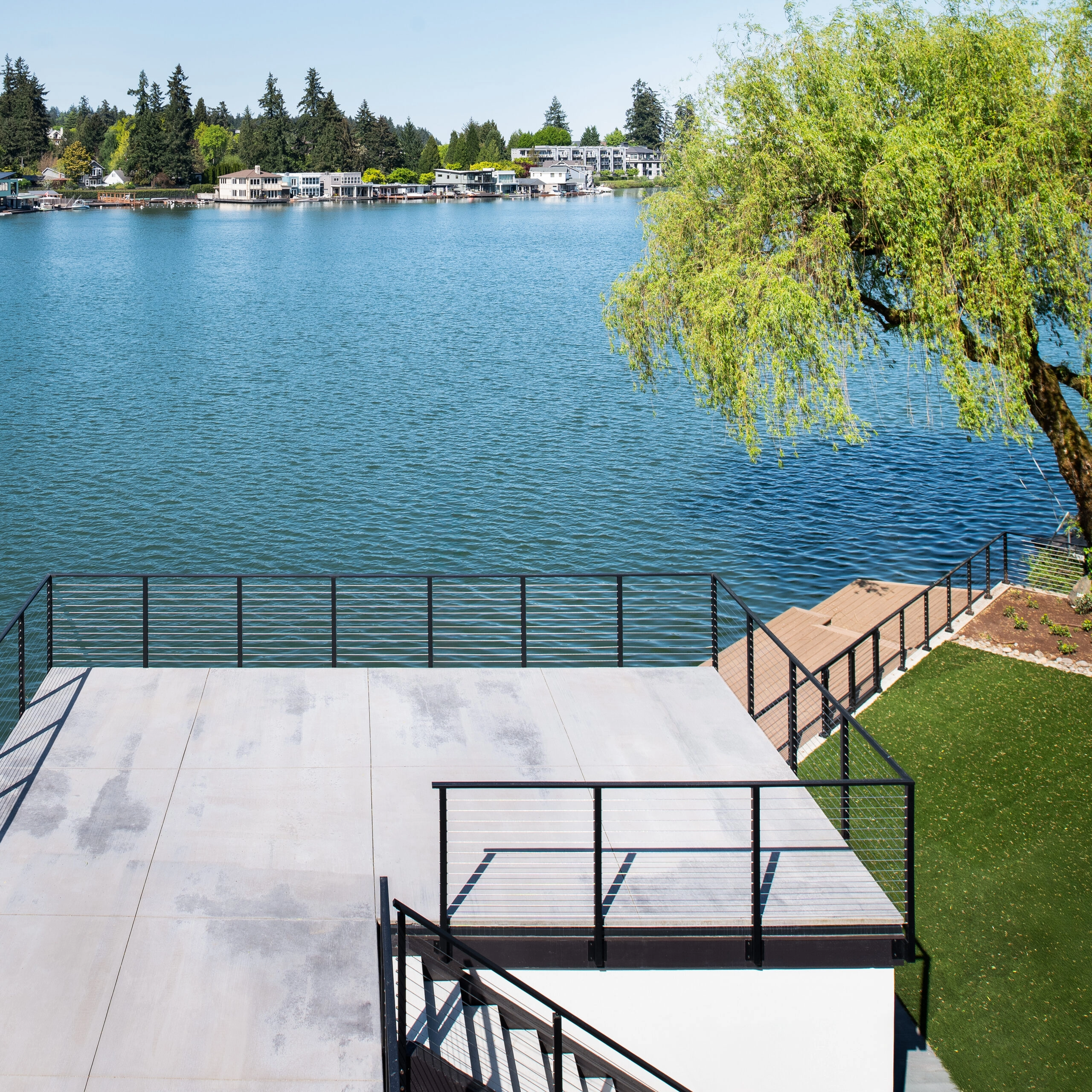 Elevated view of patio levels, stairs and railing beside a willow tree