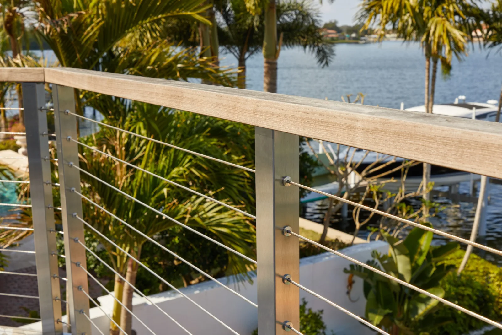 Cable railing with stainless posts running along a canal lined with palms