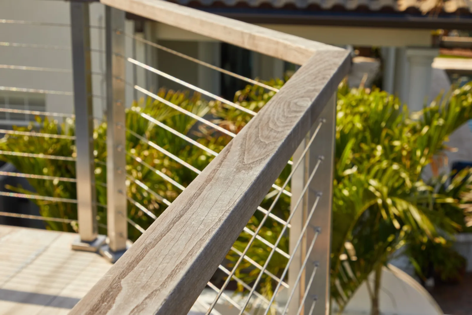 Close view of a weathered wood top rail above taut stainless cable runs