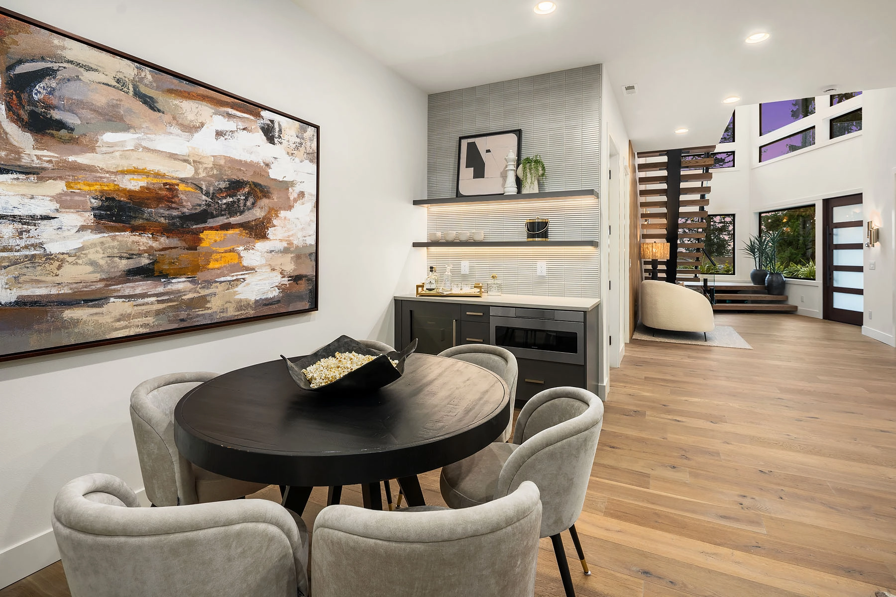 Dining area with round table and artwork, floating stair visible through the open plan