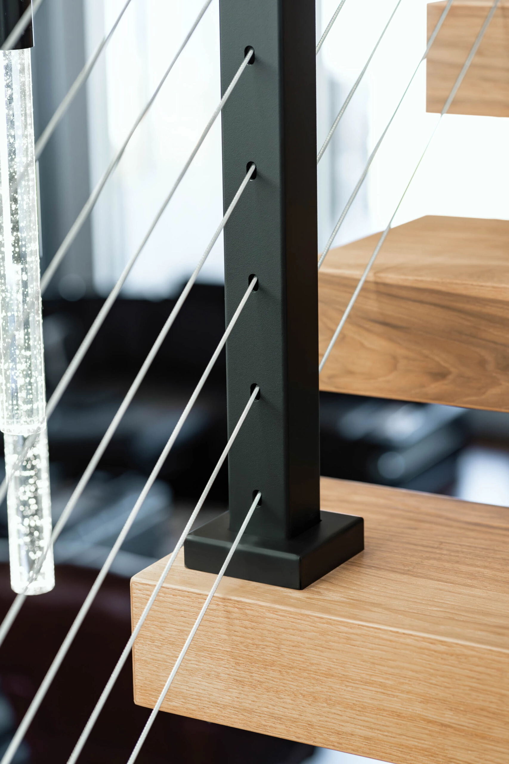 Cable railing post anchored to a wood tread with taut horizontal cables