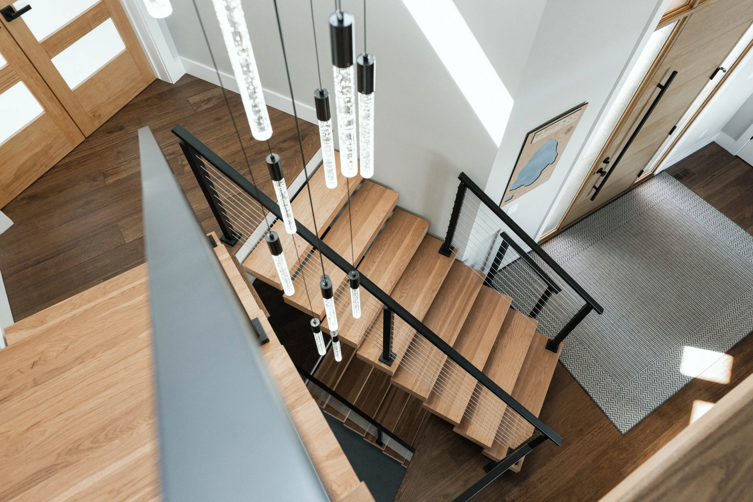 Looking down the stair from the landing past a cluster of hanging pendants