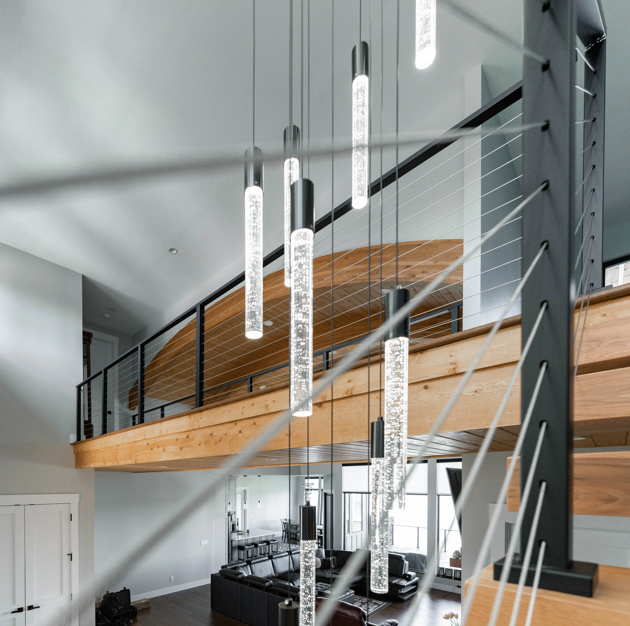 Pendant cluster hanging in the two-story space beside the balcony cable railing
