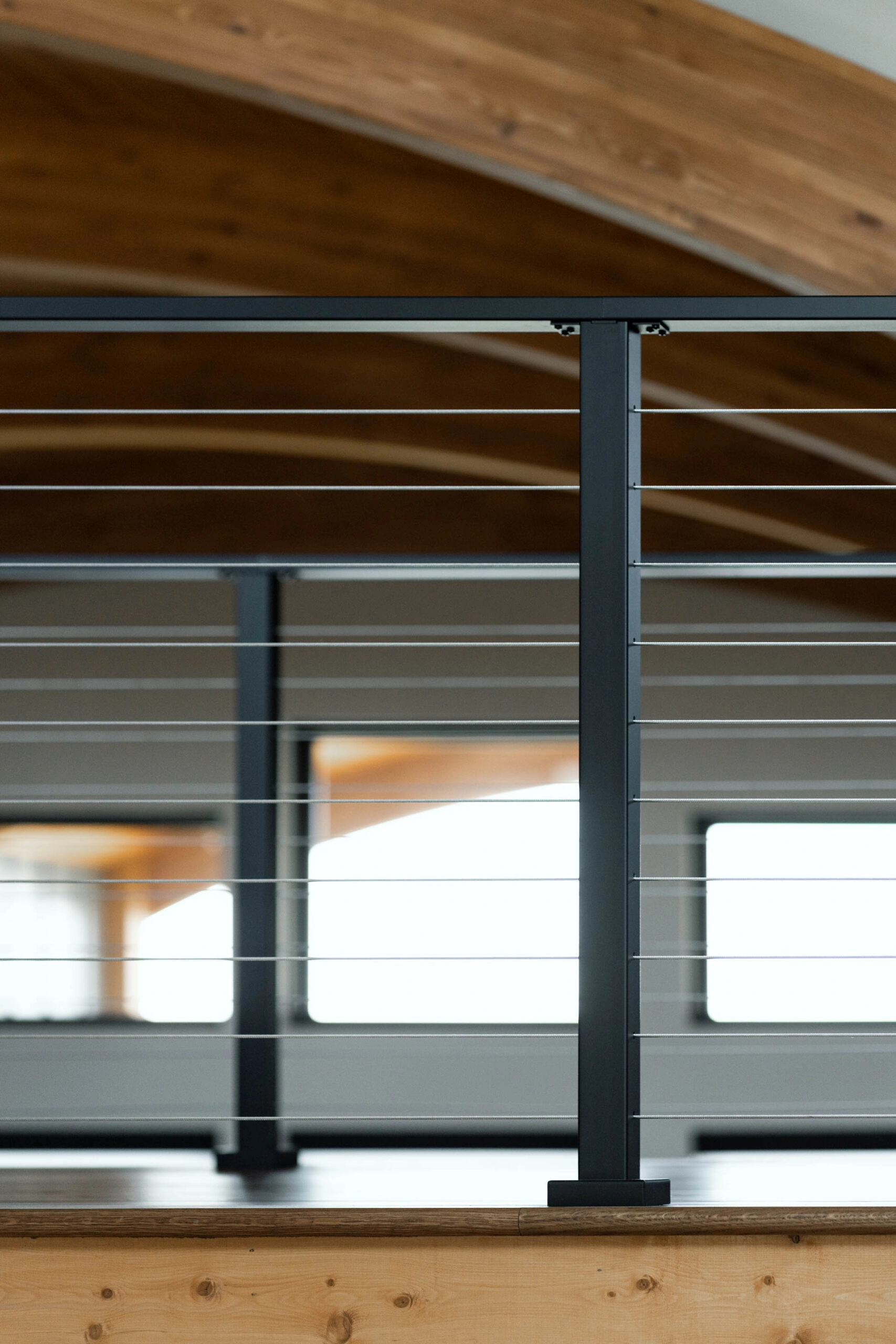 Single post and top rail at the balcony edge below the arched wood ceiling
