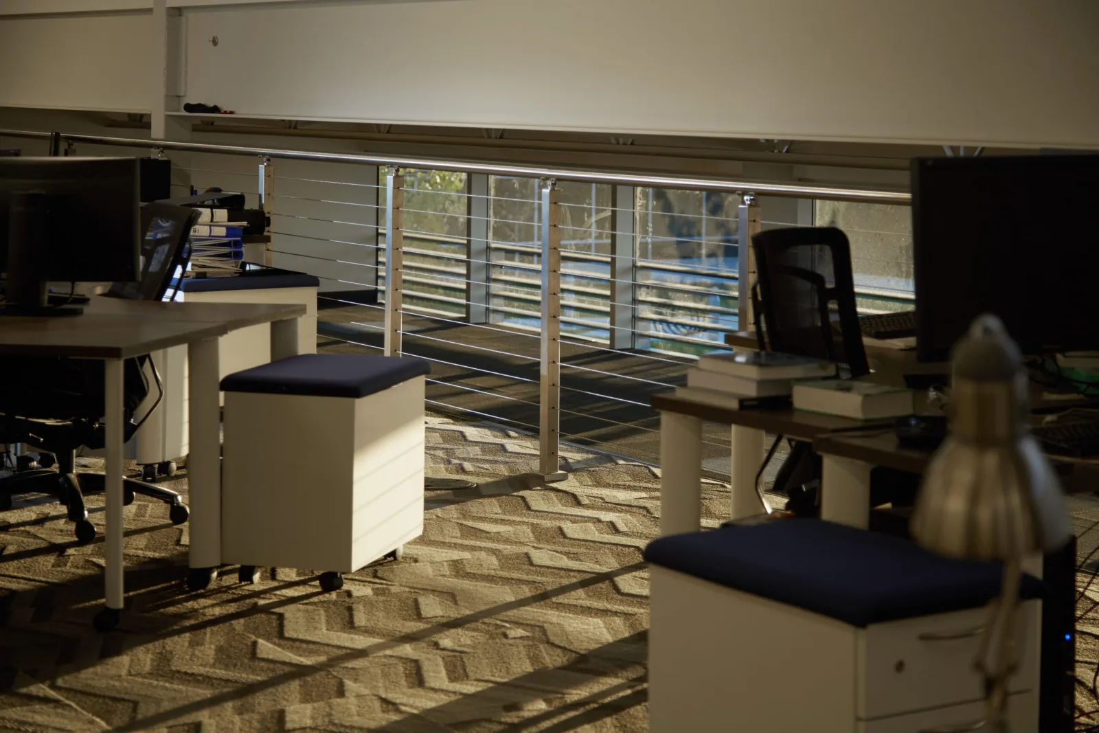 Laboratory office desks beside stainless cable railing guarding a mezzanine opening