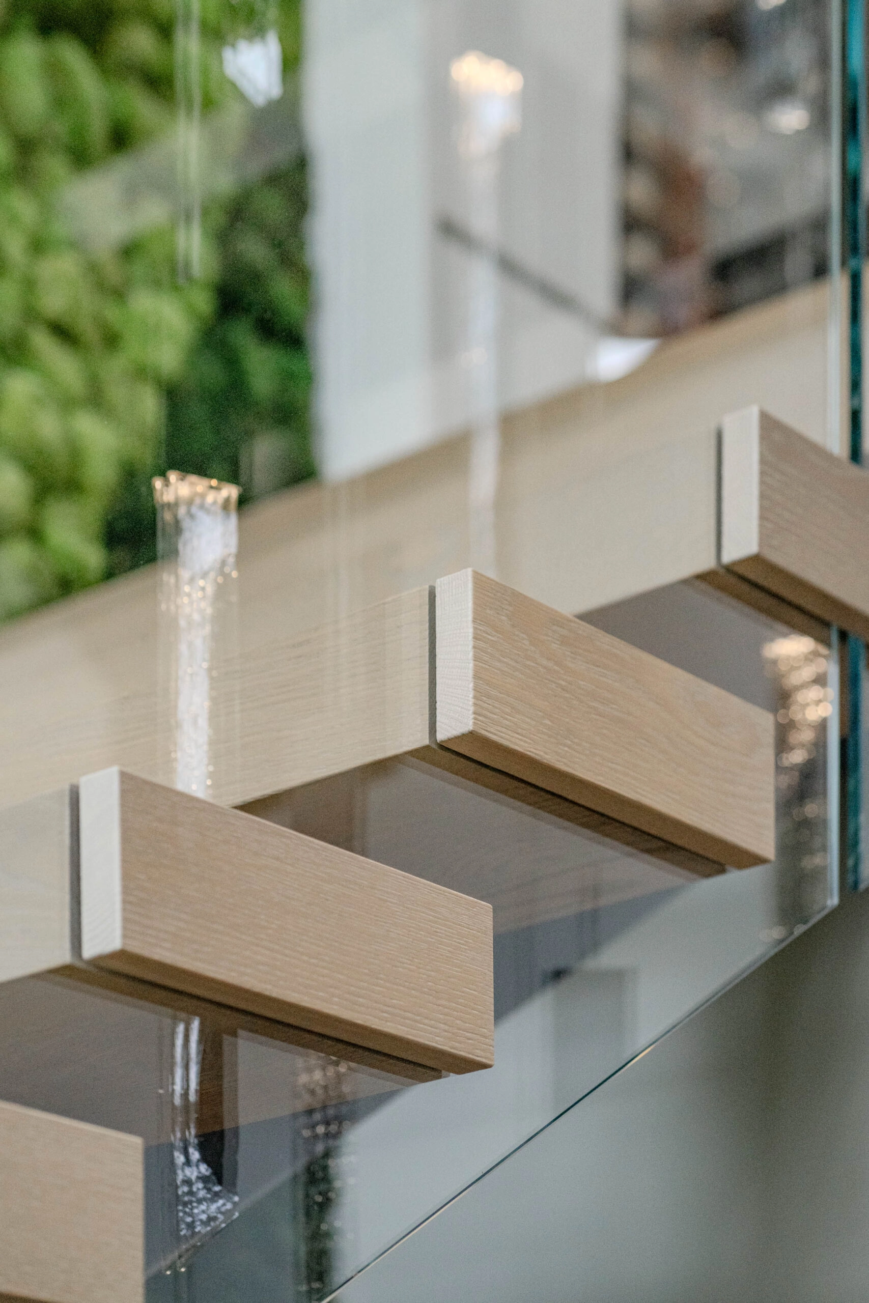 Pale cantilevered treads seen through a frameless glass panel
