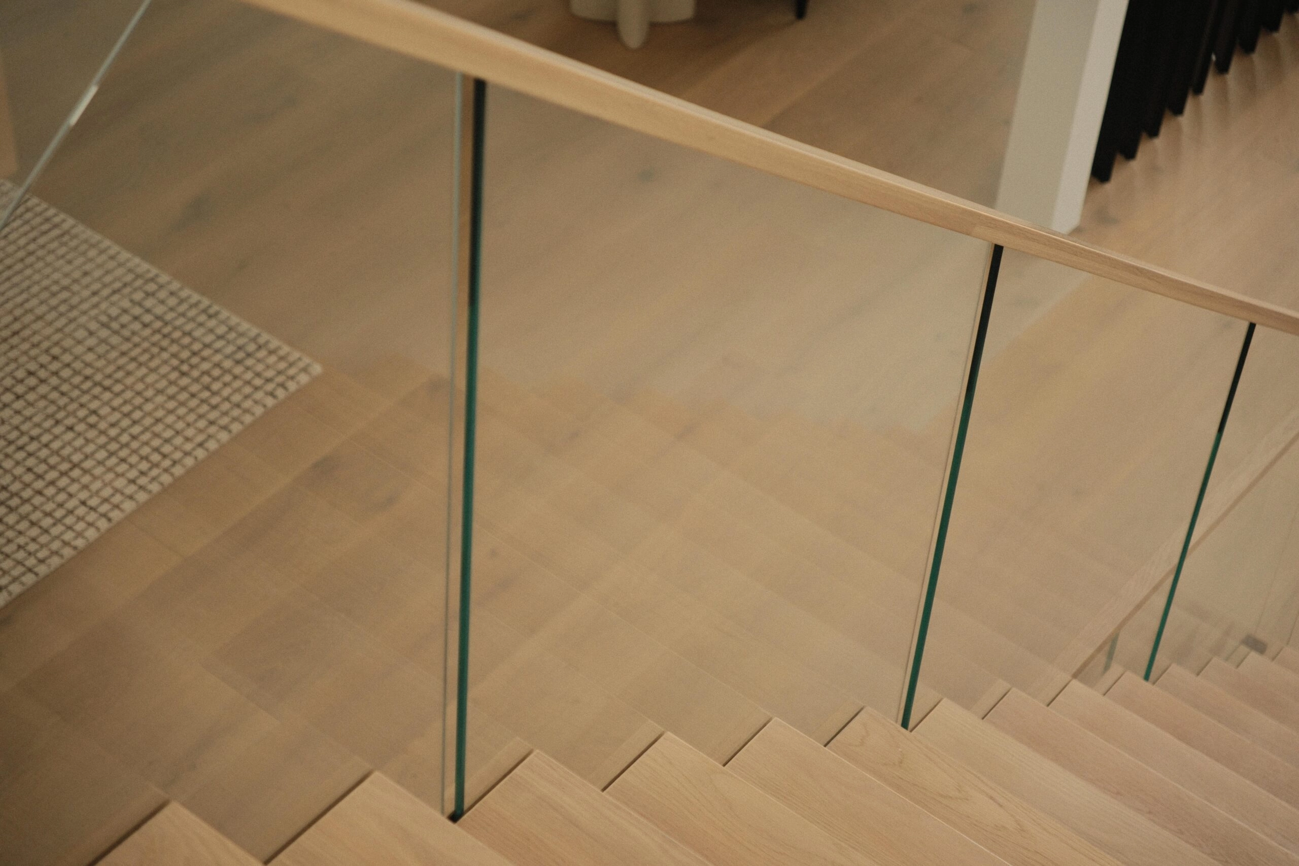 Looking down the flight past glass panels topped by a wood handrail