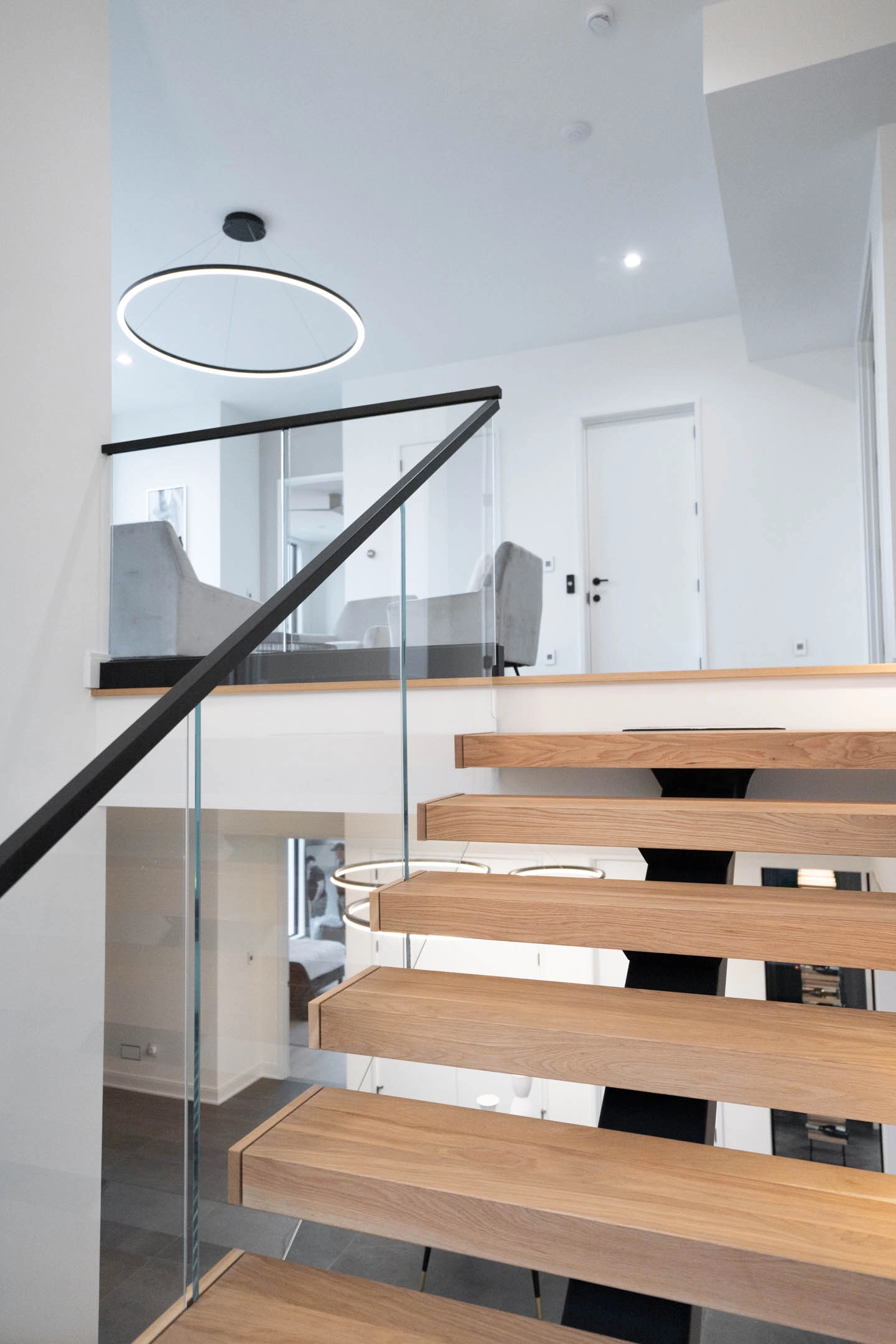 Ring pendant above the landing where the glass railing meets a wood cap rail
