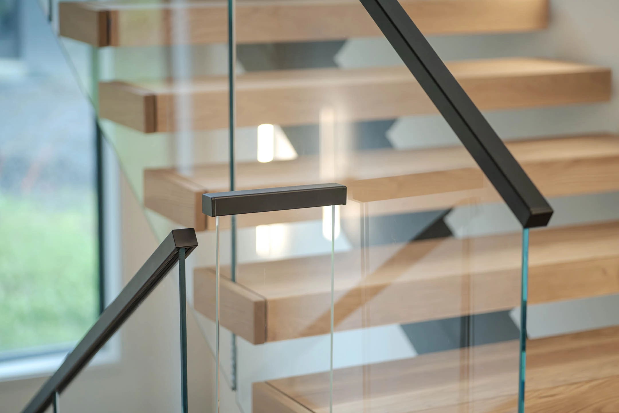Handrail bracket clamped to the glass panel with treads receding behind