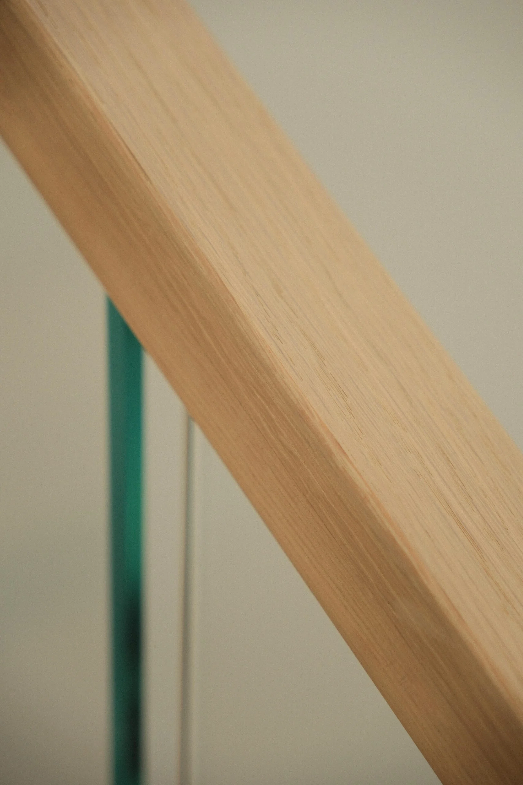 Macro of the wood handrail meeting the edge of a glass panel