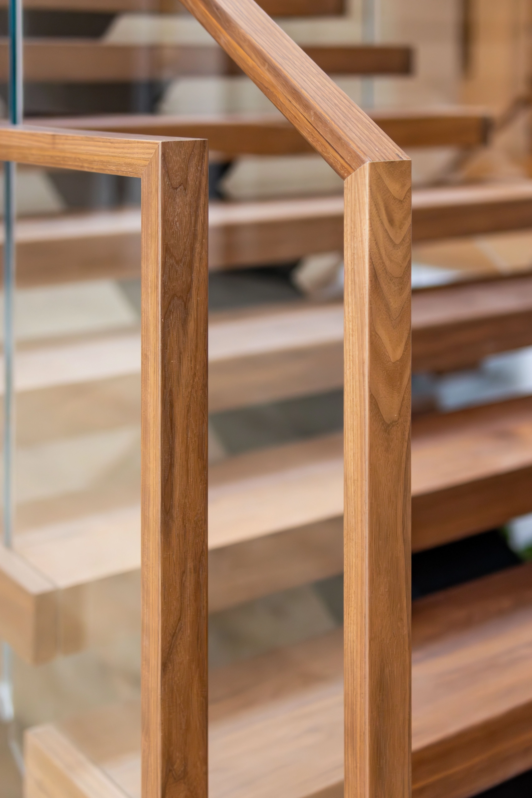 Detail of the wood newel post and rail frame holding a glass panel