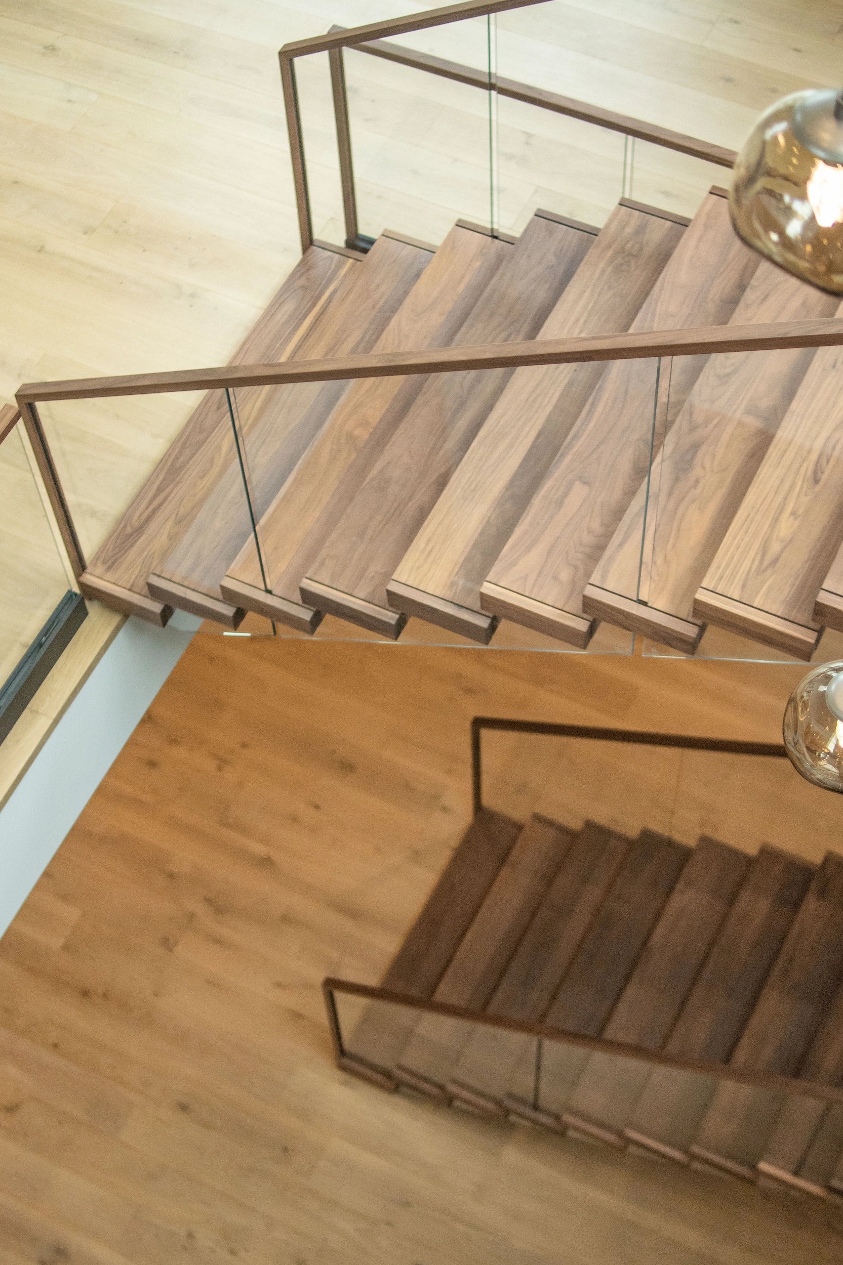 Looking down on extra-wide treads and the glass railing from the upper level
