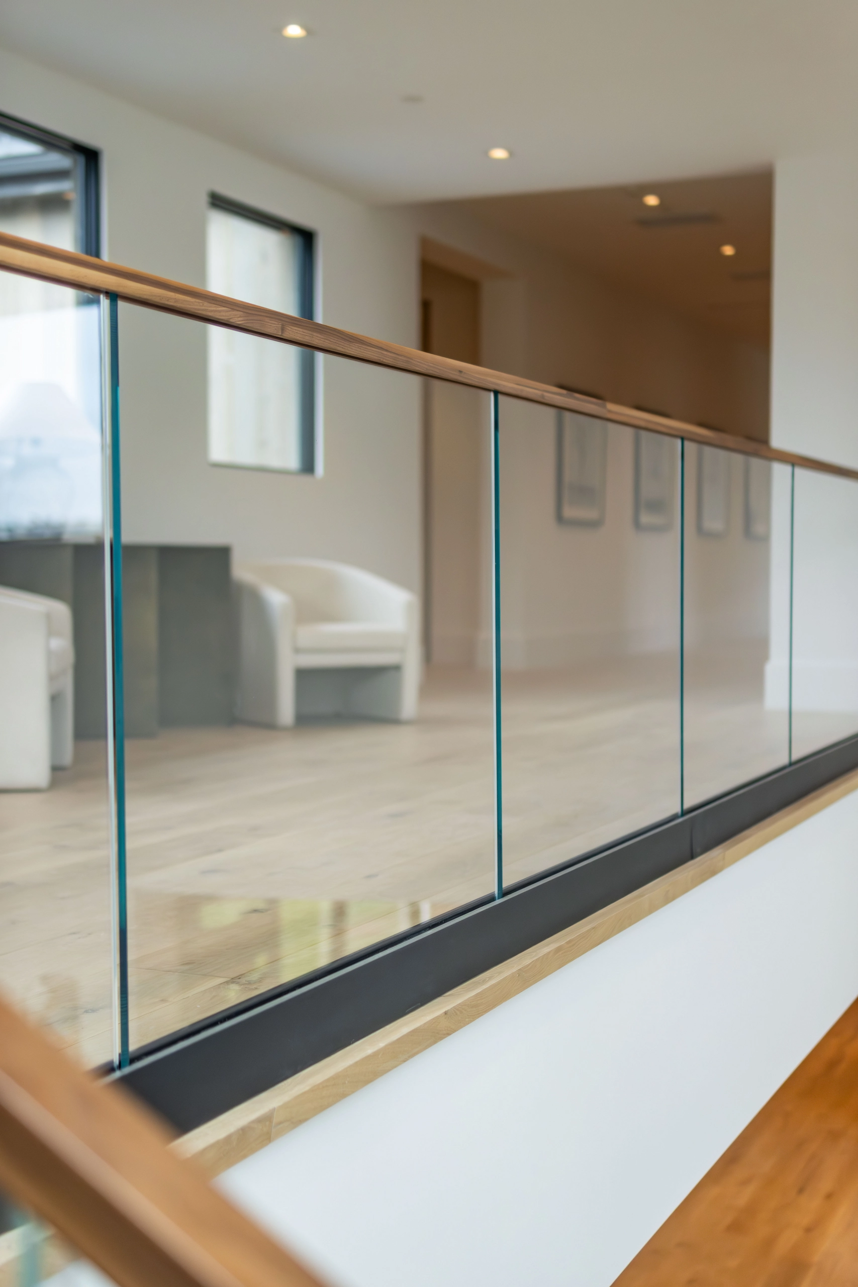Balcony glass railing on a black base shoe with a wood top rail