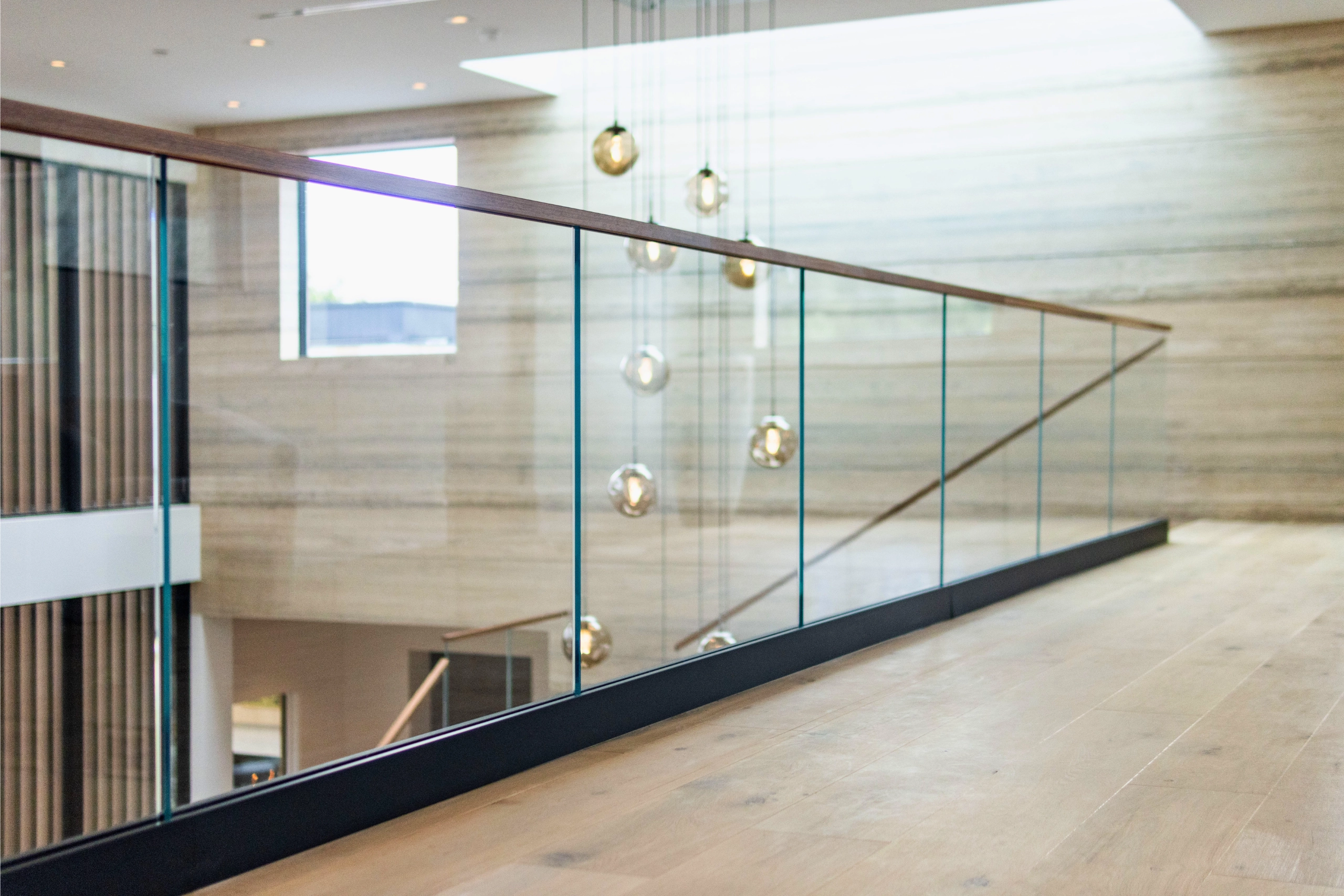 Long overlook run of glass panels below hanging globes and a stone wall