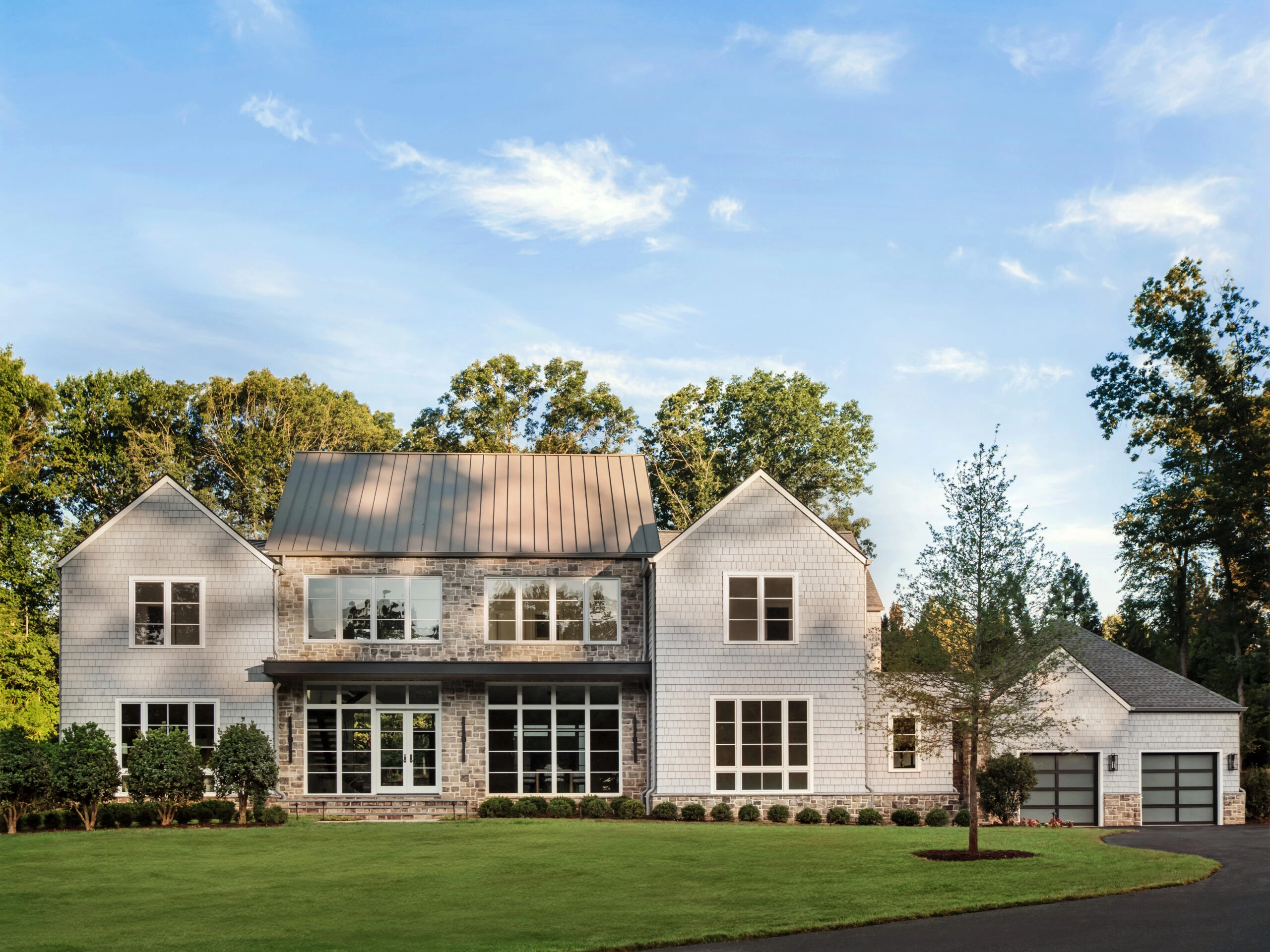 White shingled house with a standing-seam metal roof behind a broad green lawn
