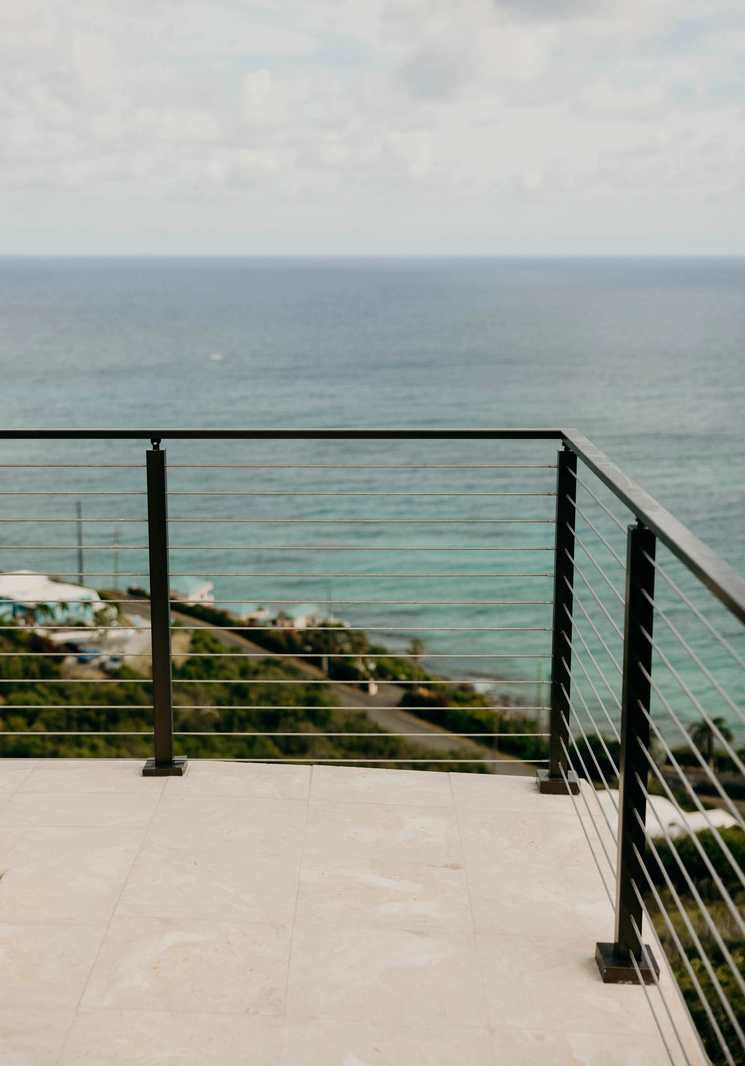 Rod railing turning a corner on a stone terrace facing the open sea