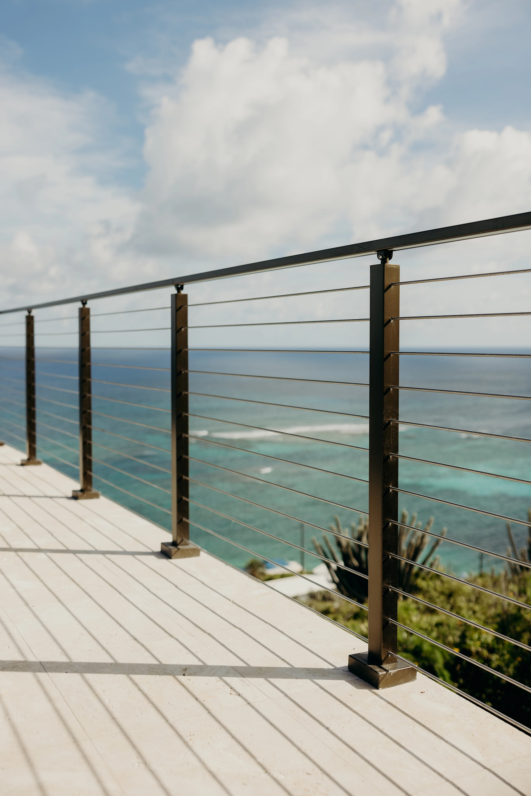 Rod railing running along a light plank deck above a shallow reef