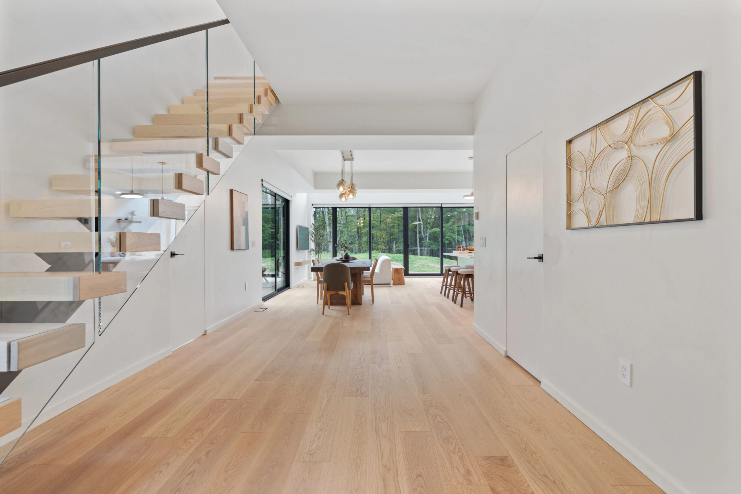 Hallway with plank floor looking toward the stair and a glass dining wall