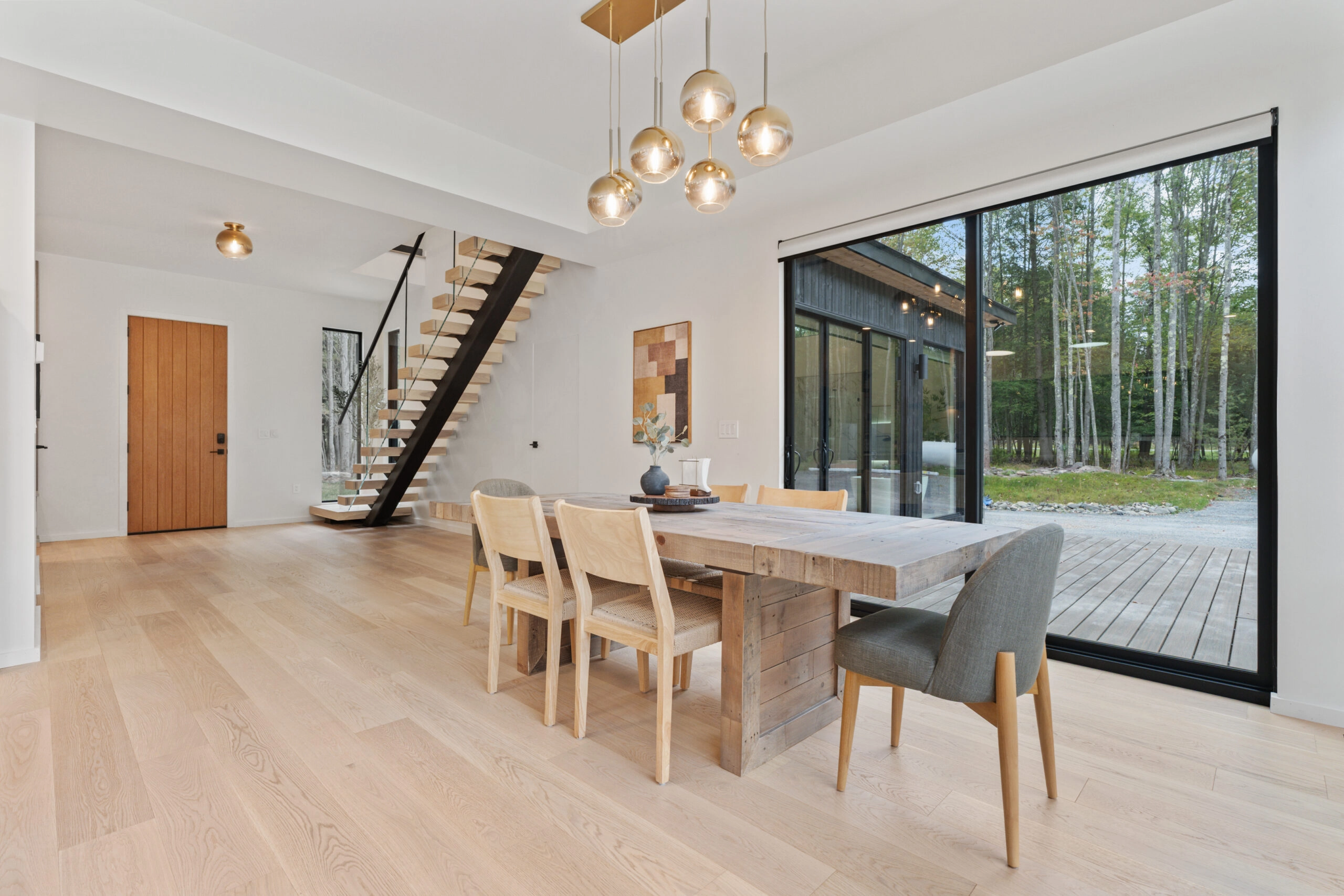Dining table under glass pendants with the stair in the far corner