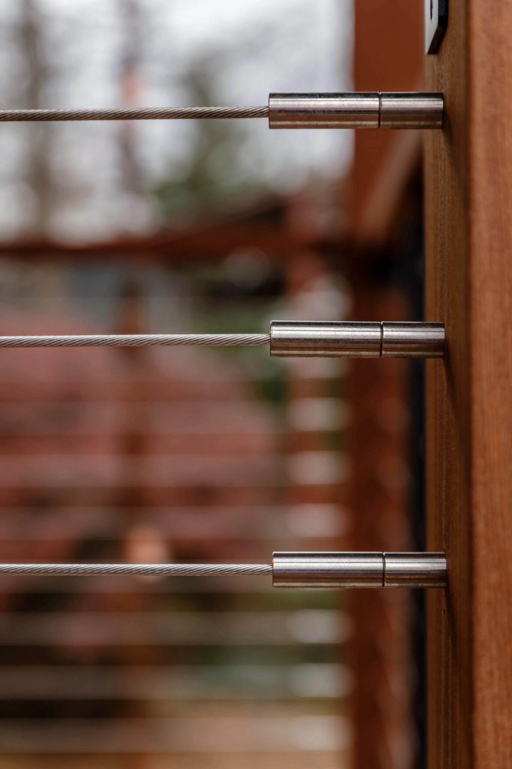 Close view of cable tensioners set into a wood post, blurred deck behind