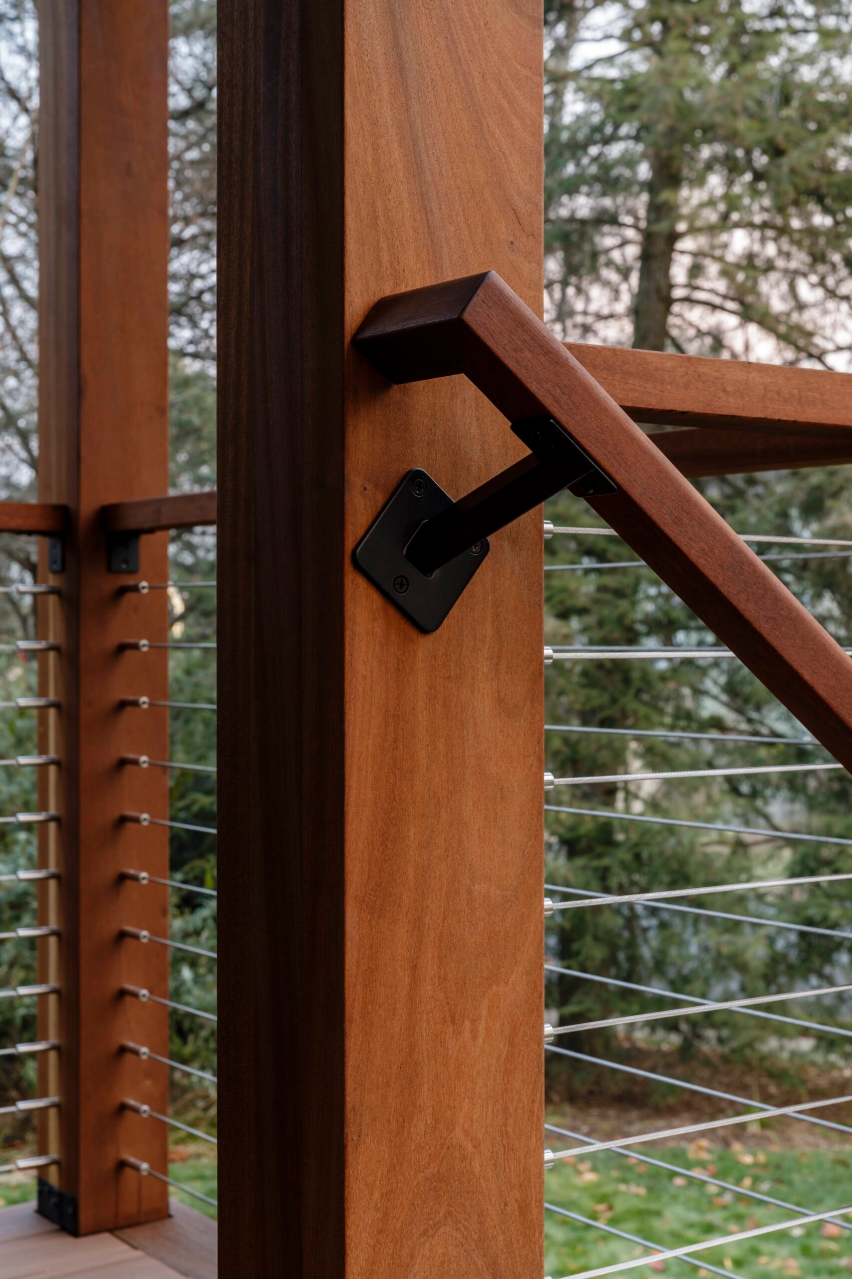 Bracket where a wood handrail meets a post above cable infill